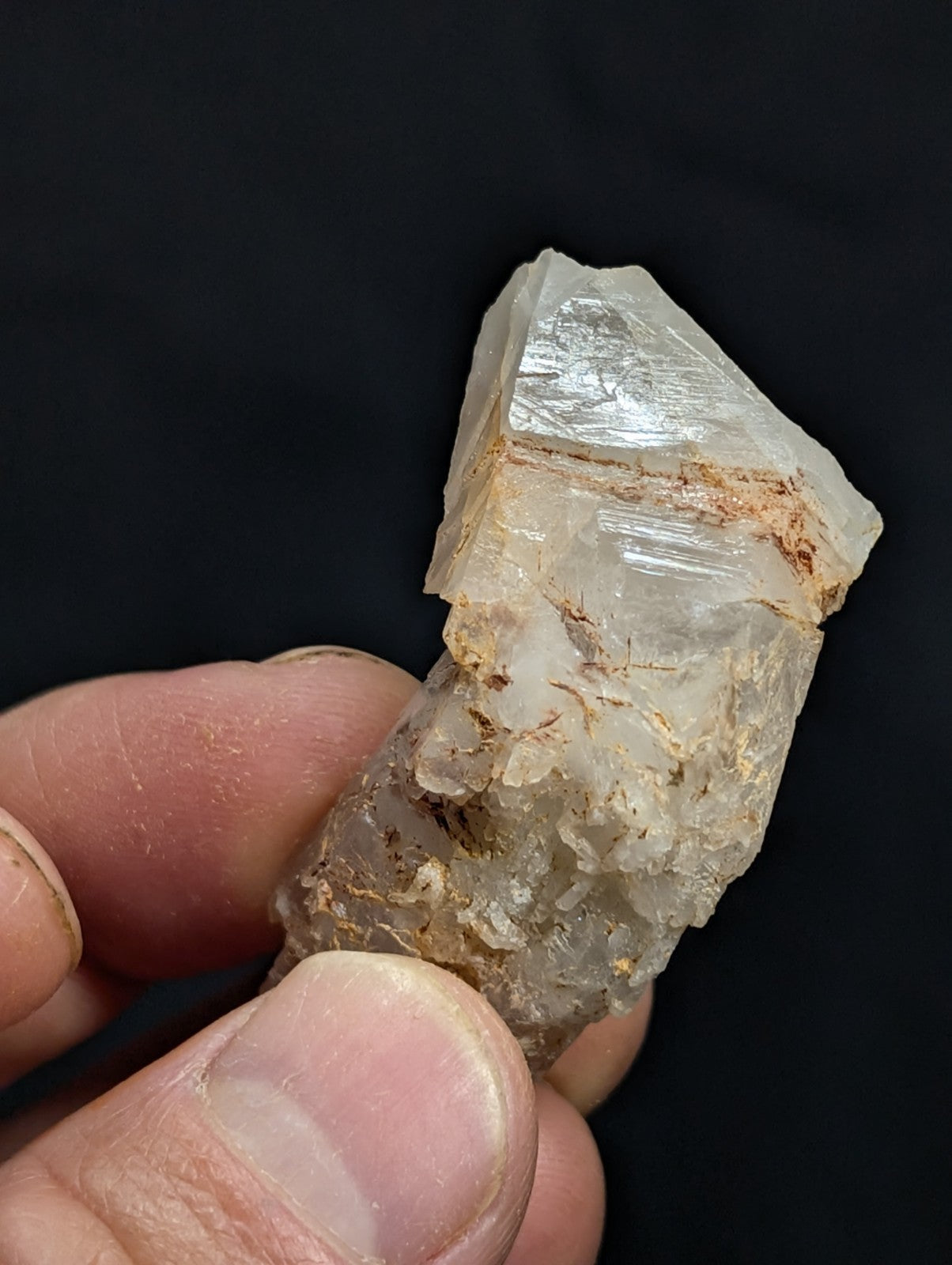 A translucent, crystalline quartz specimen with natural striations and earthy brown inclusions.