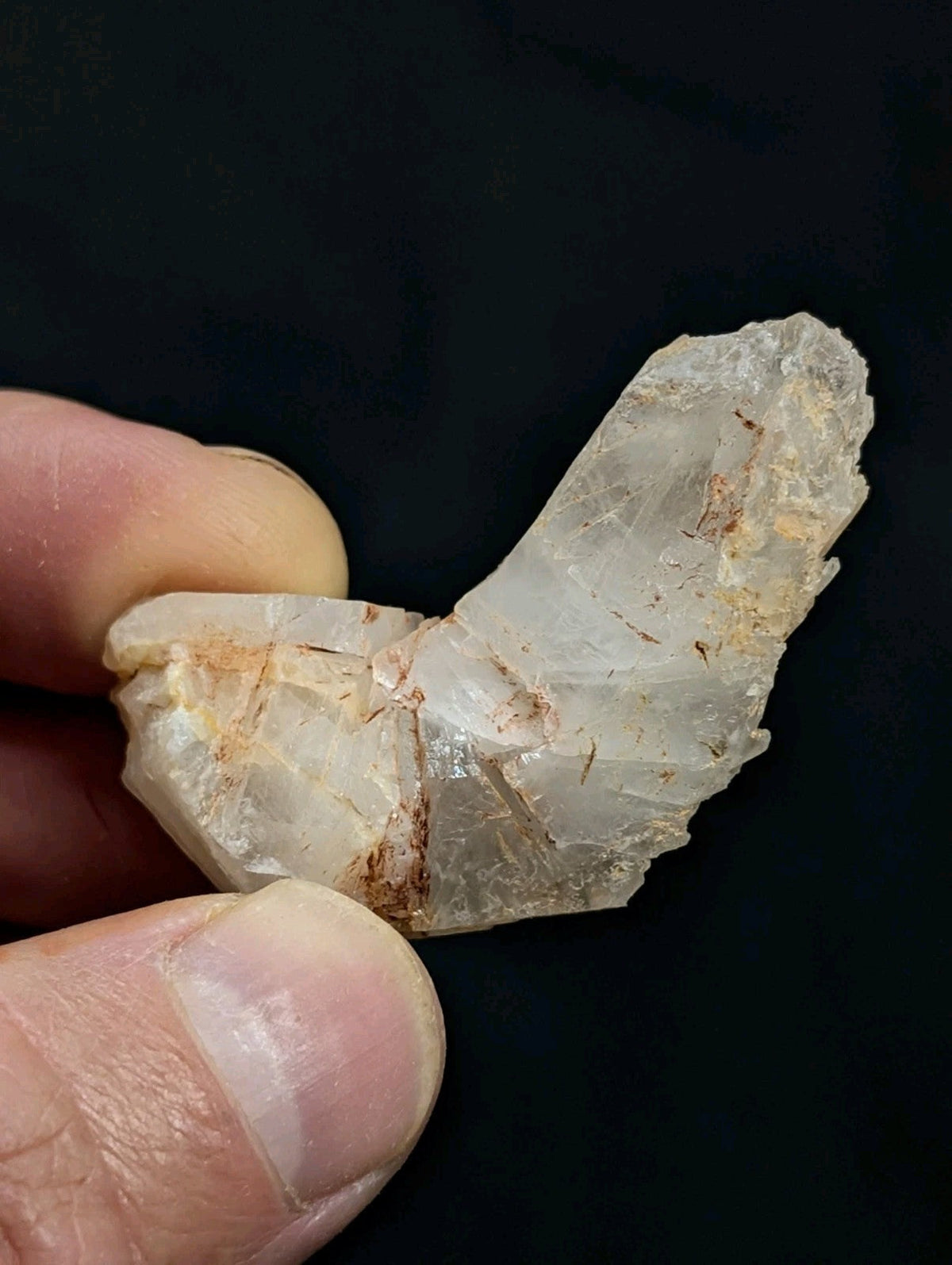 A translucent, pale quartz crystal with natural facets and subtle brown inclusions.