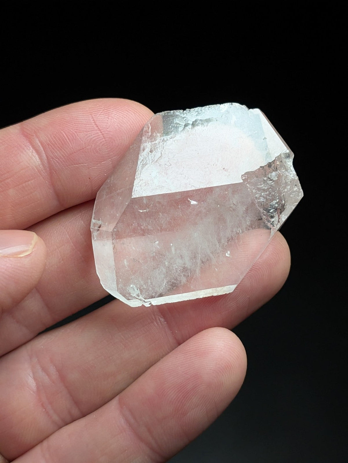 A translucent, clear quartz crystal with a faceted, geometric shape and natural internal inclusions.