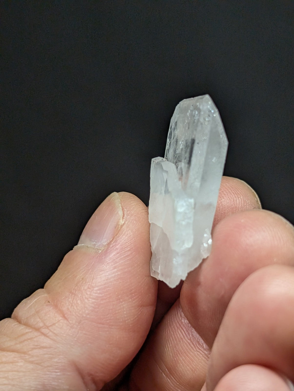 A translucent, clear quartz crystal with a pointed tip and natural facets.
