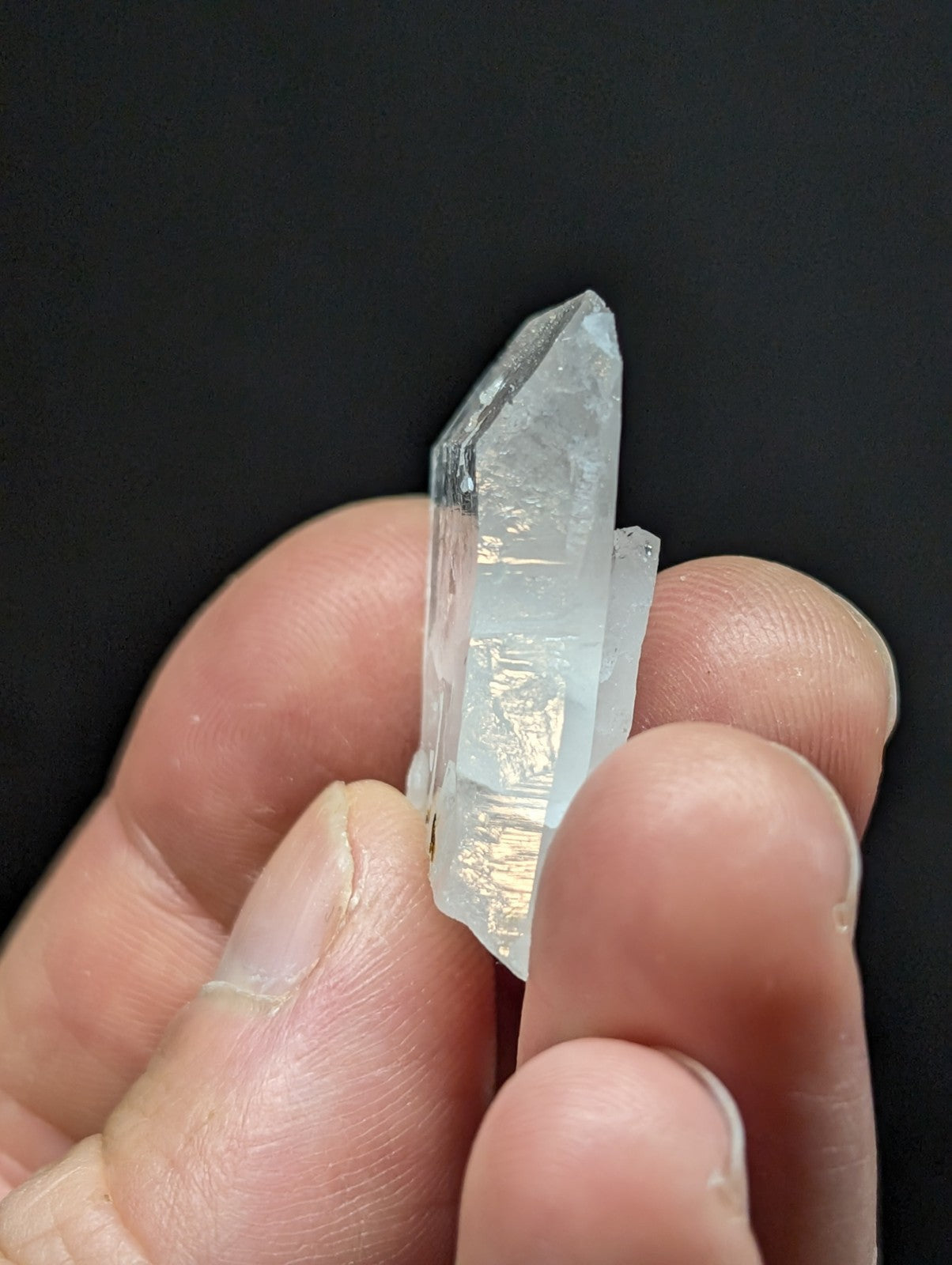 A translucent, clear quartz crystal with a pointed tip and visible internal striations.