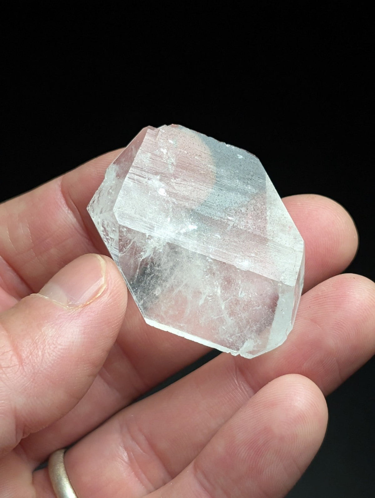 A translucent, hexagonal quartz crystal with visible internal striations and a slightly cloudy appearance.