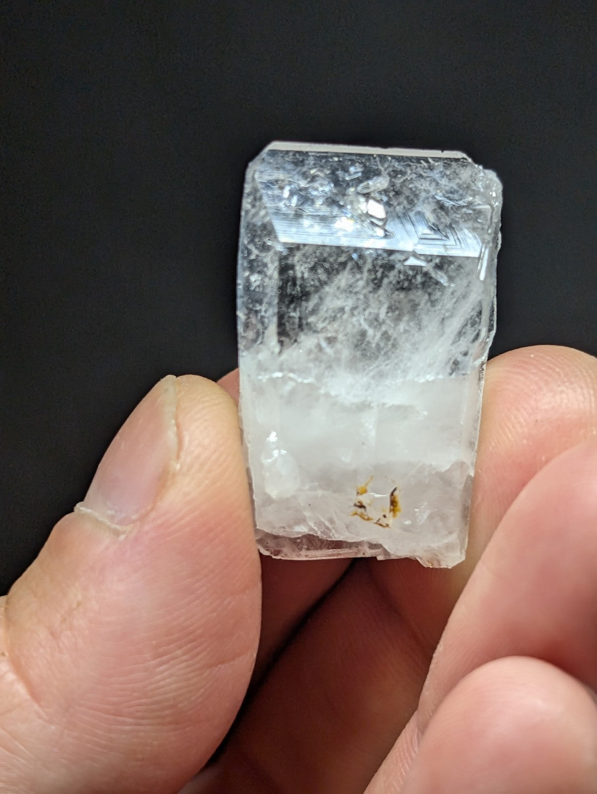 A translucent, clear quartz crystal with visible internal inclusions and a rough, faceted surface.