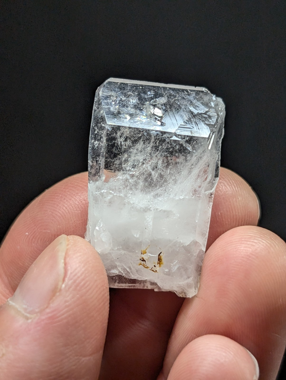 A translucent, clear quartz crystal with visible internal inclusions and a faceted top surface.