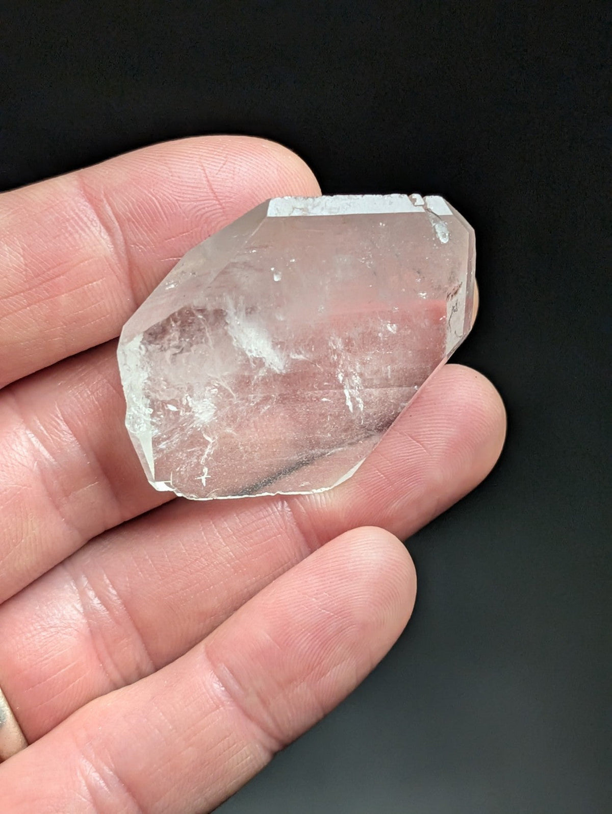 A translucent, faceted quartz crystal with a natural, irregular shape and subtle internal inclusions.