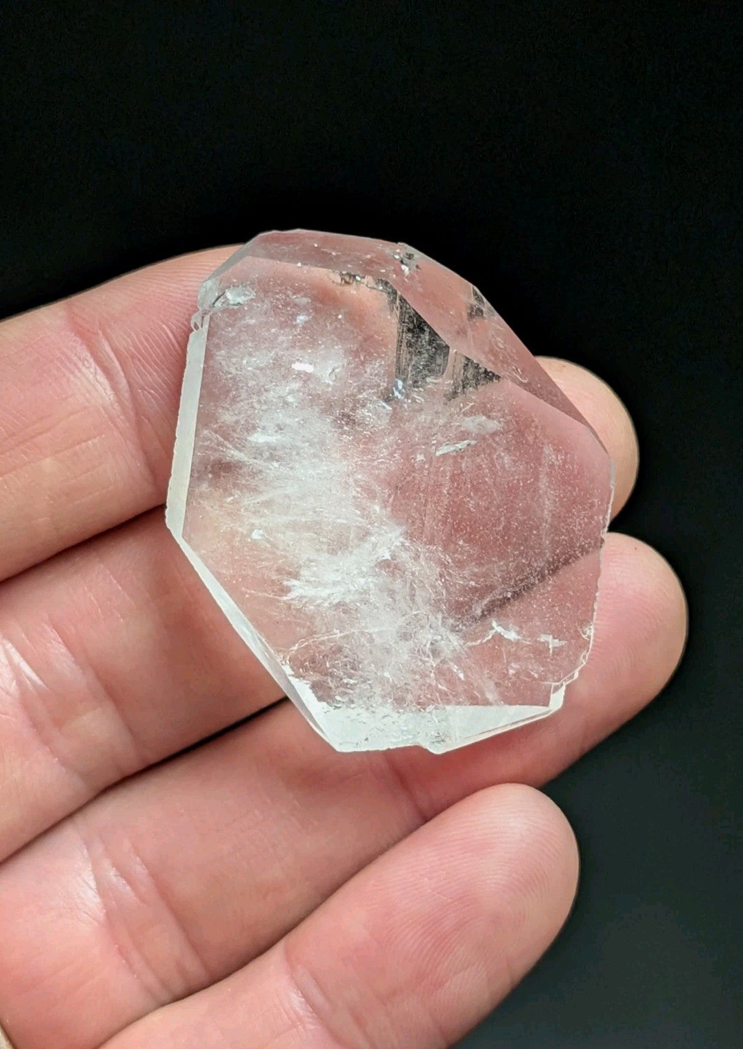 A translucent, pale pink quartz crystal with natural internal inclusions and a faceted surface.