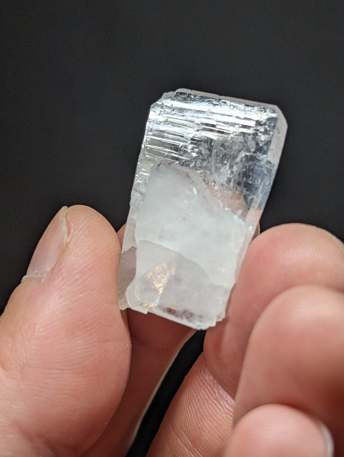 A translucent, clear quartz crystal with visible internal striations and a rough, natural edge.
