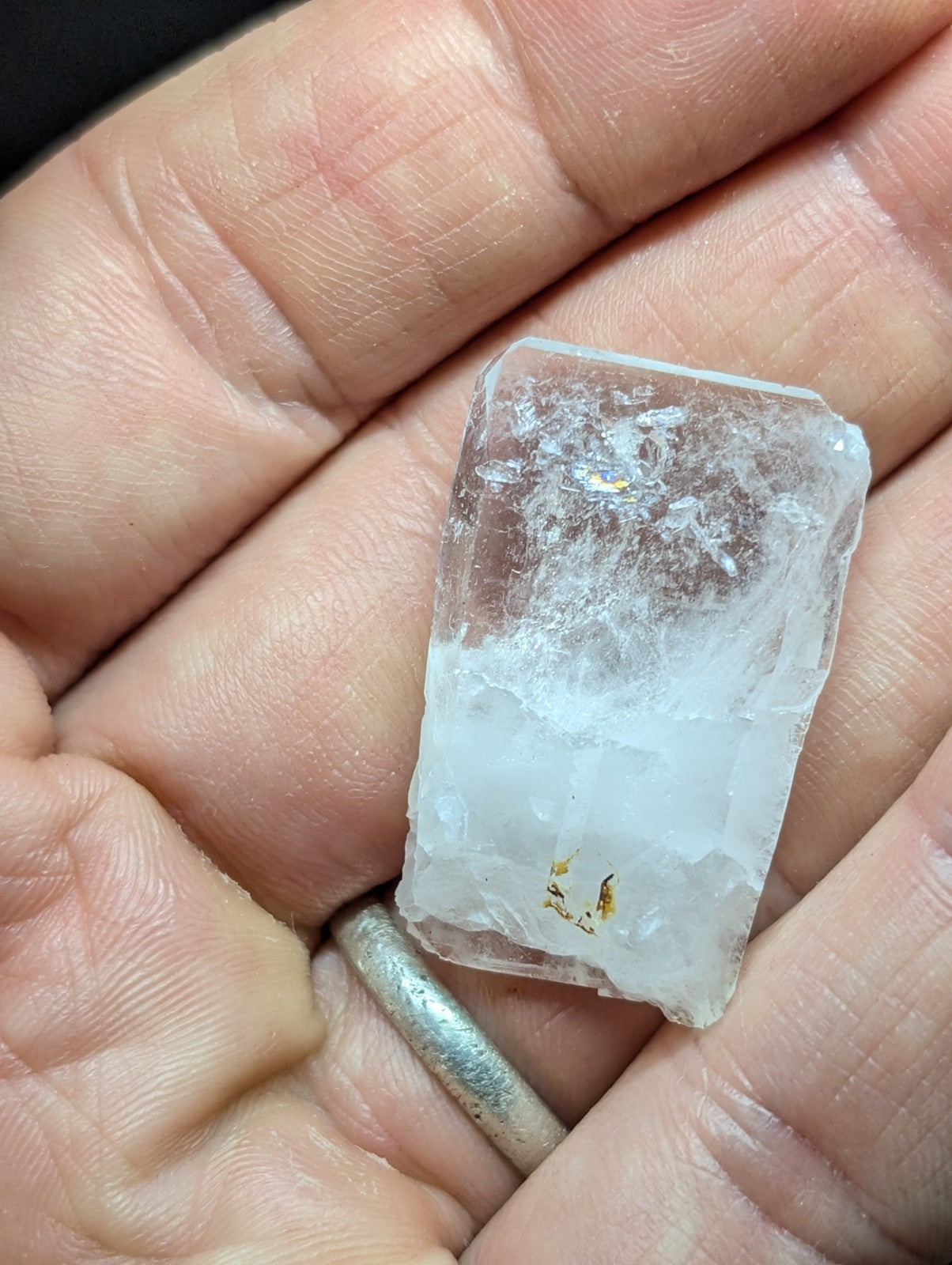 A translucent, irregularly shaped crystal with a slightly cloudy appearance and faint golden inclusions.