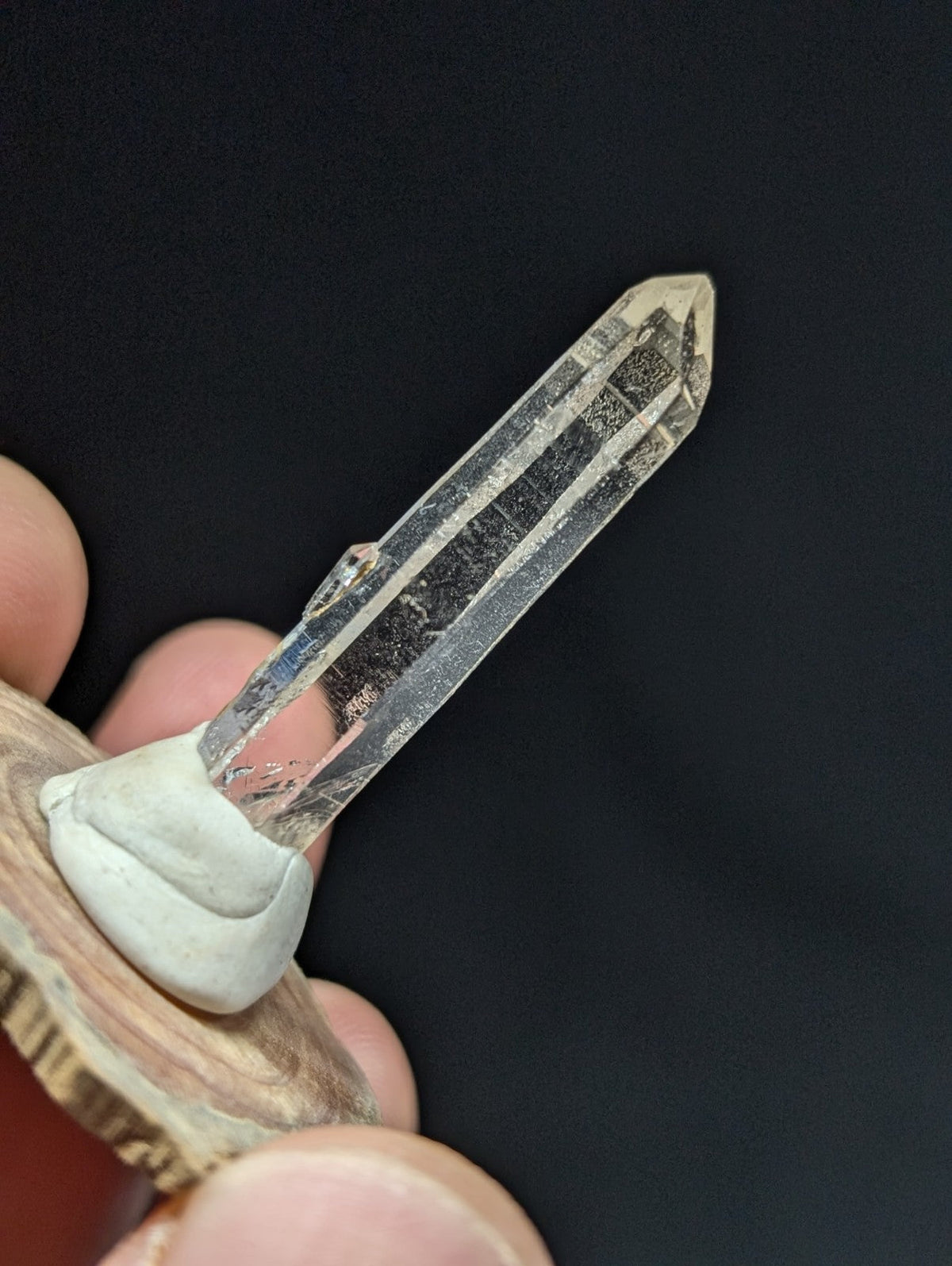 A clear, faceted quartz crystal with natural inclusions and a pointed tip.