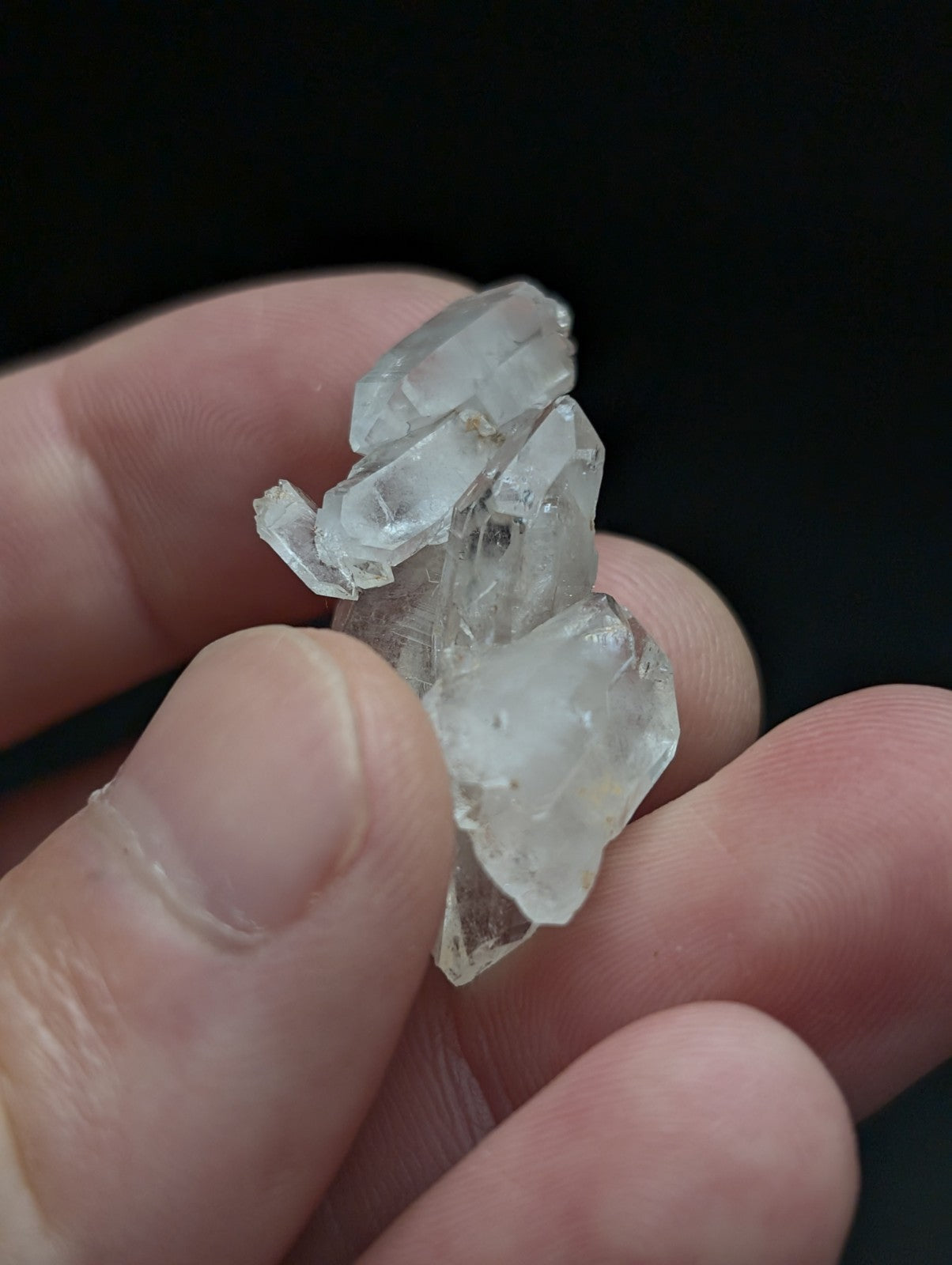 A cluster of clear double terminated floater quartz crystals with sharp edges held in a hand from Arkansas