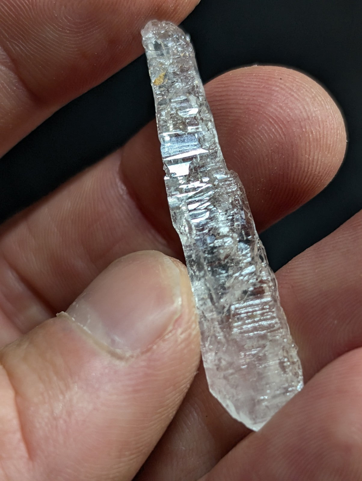 A clear, translucent quartz crystal with visible internal striations and a pointed tip.