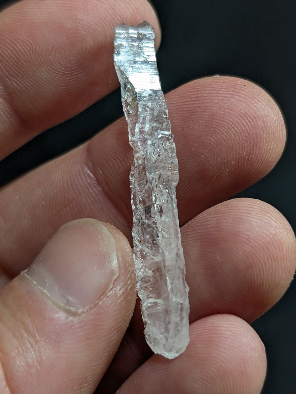 A translucent, clear quartz crystal with a rough, jagged surface and natural striations.