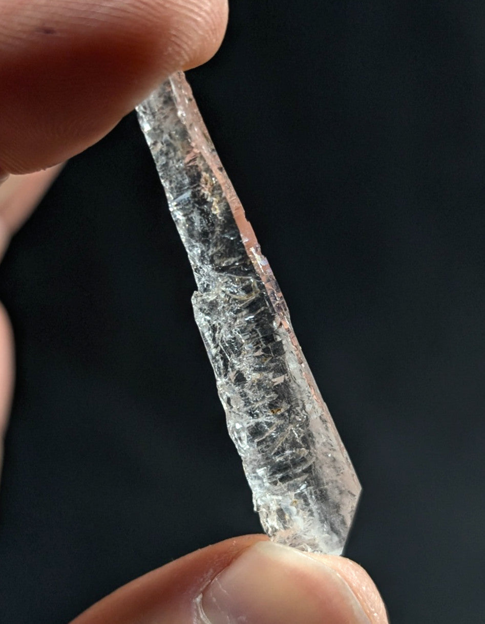 A clear, translucent quartz crystal with a pointed tip and visible internal fractures.