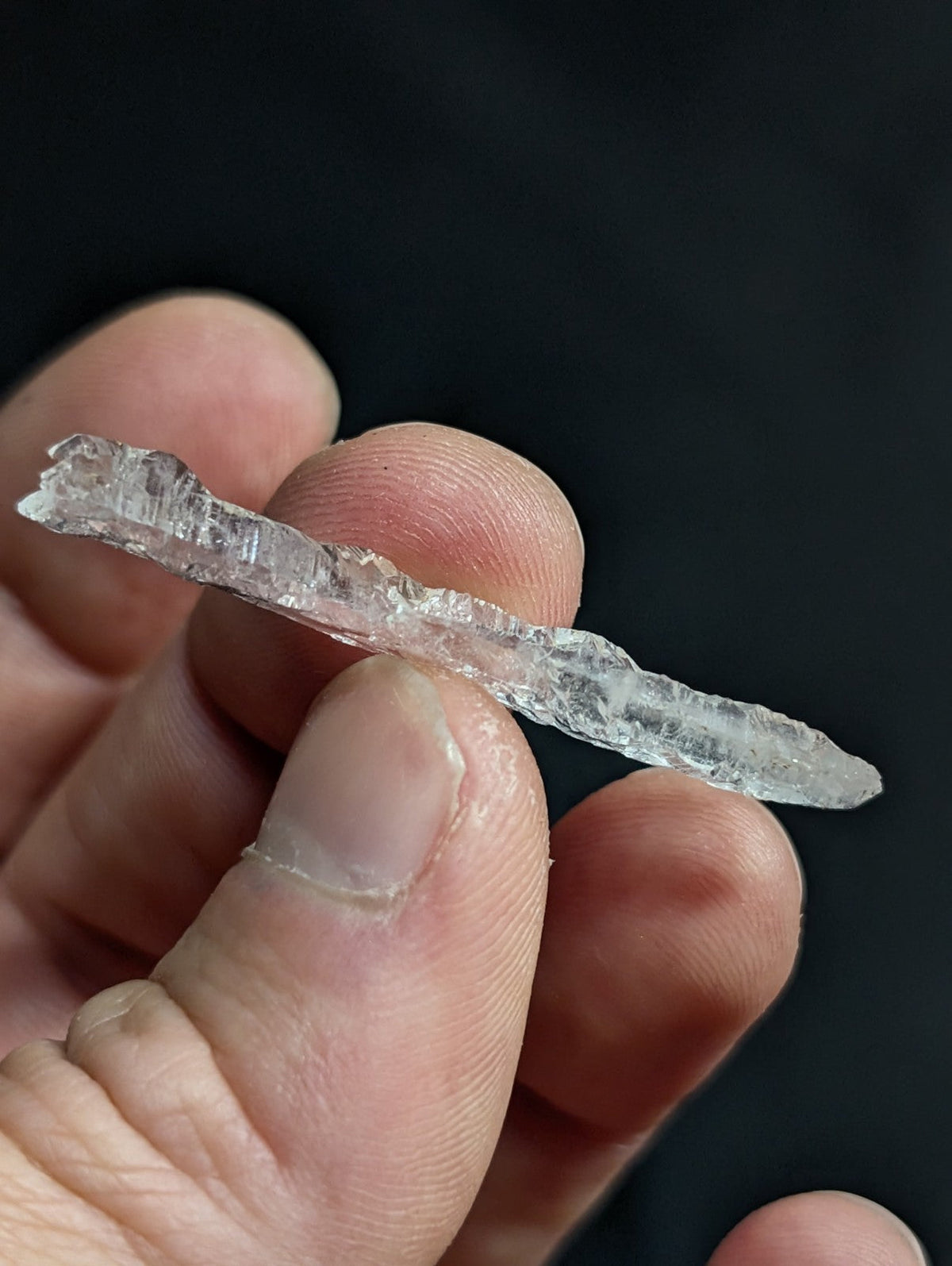 A translucent, irregularly shaped crystal with a rough, jagged surface and natural facets.
