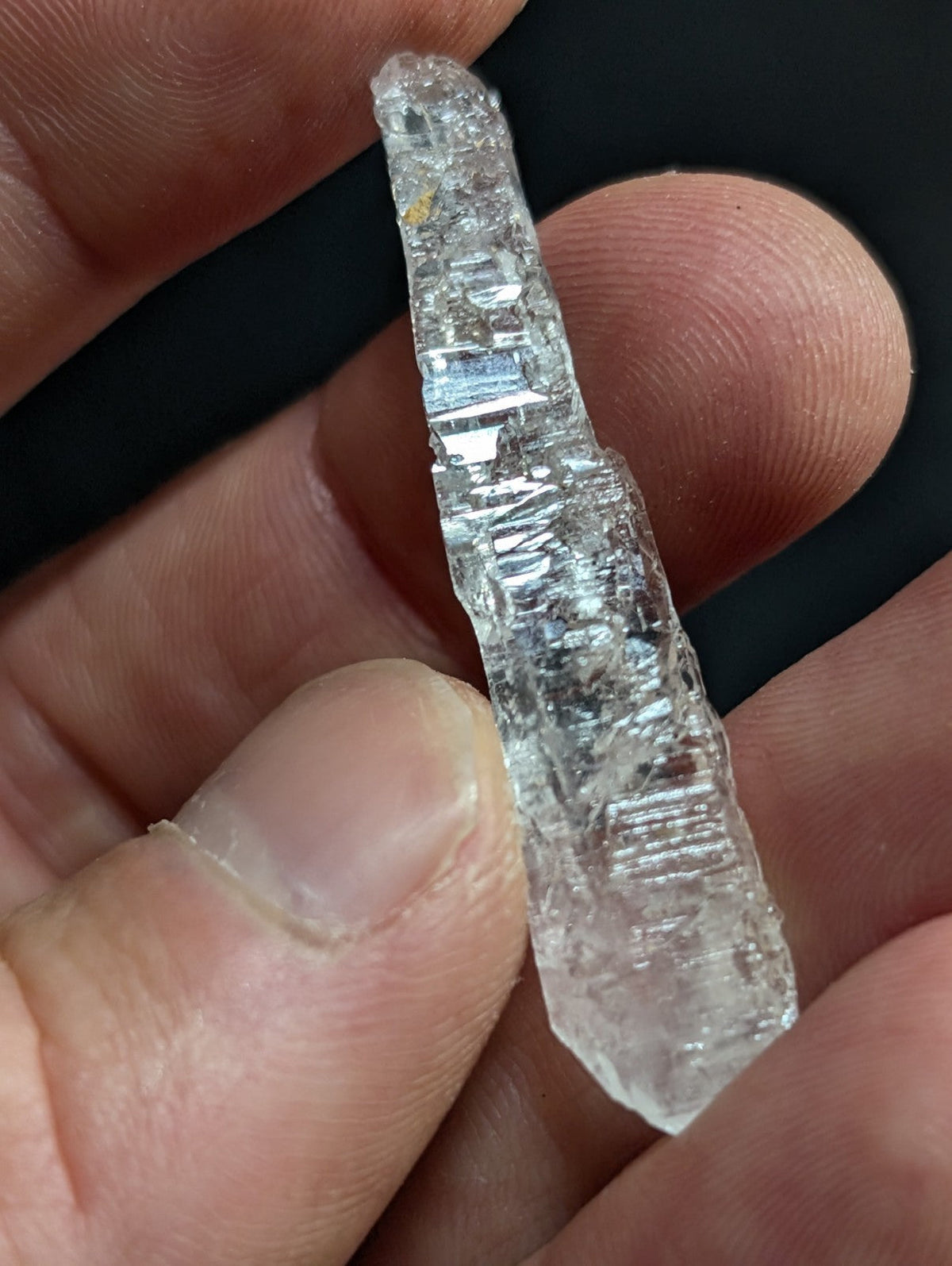 A clear, translucent quartz crystal with visible internal striations and a pointed tip.