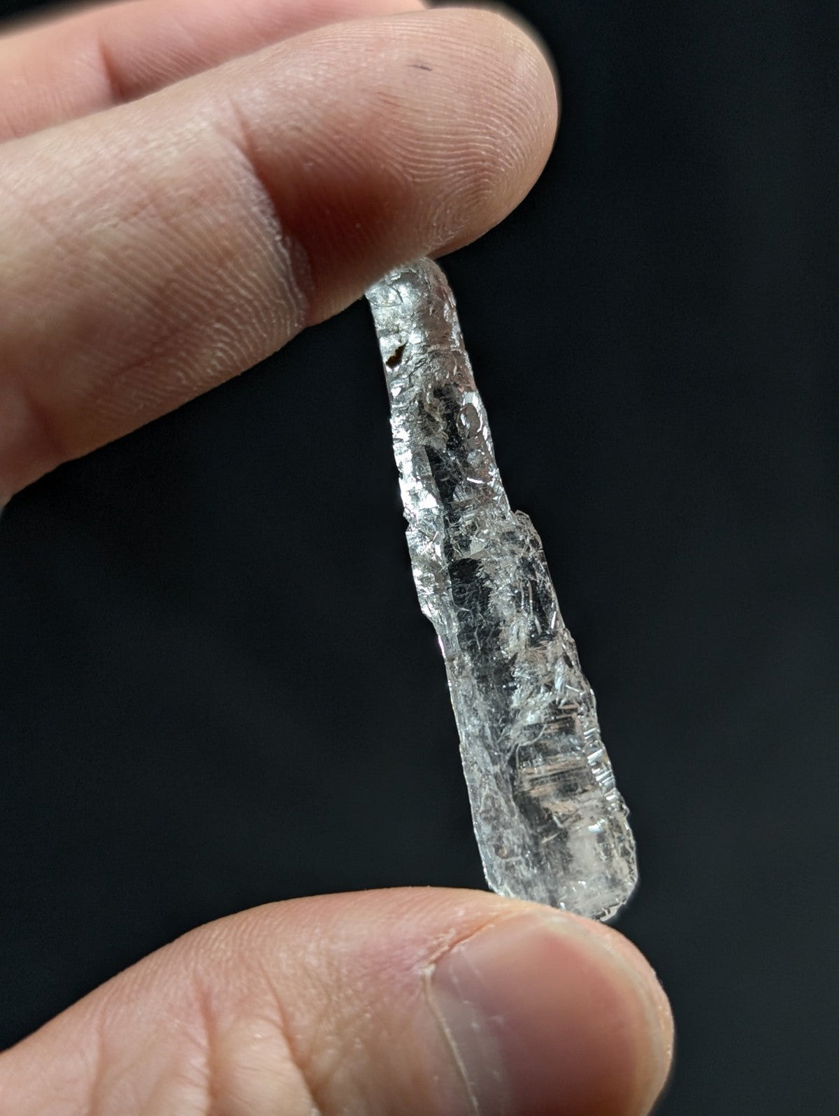 A translucent, clear quartz crystal with a rough, jagged surface and natural internal inclusions.