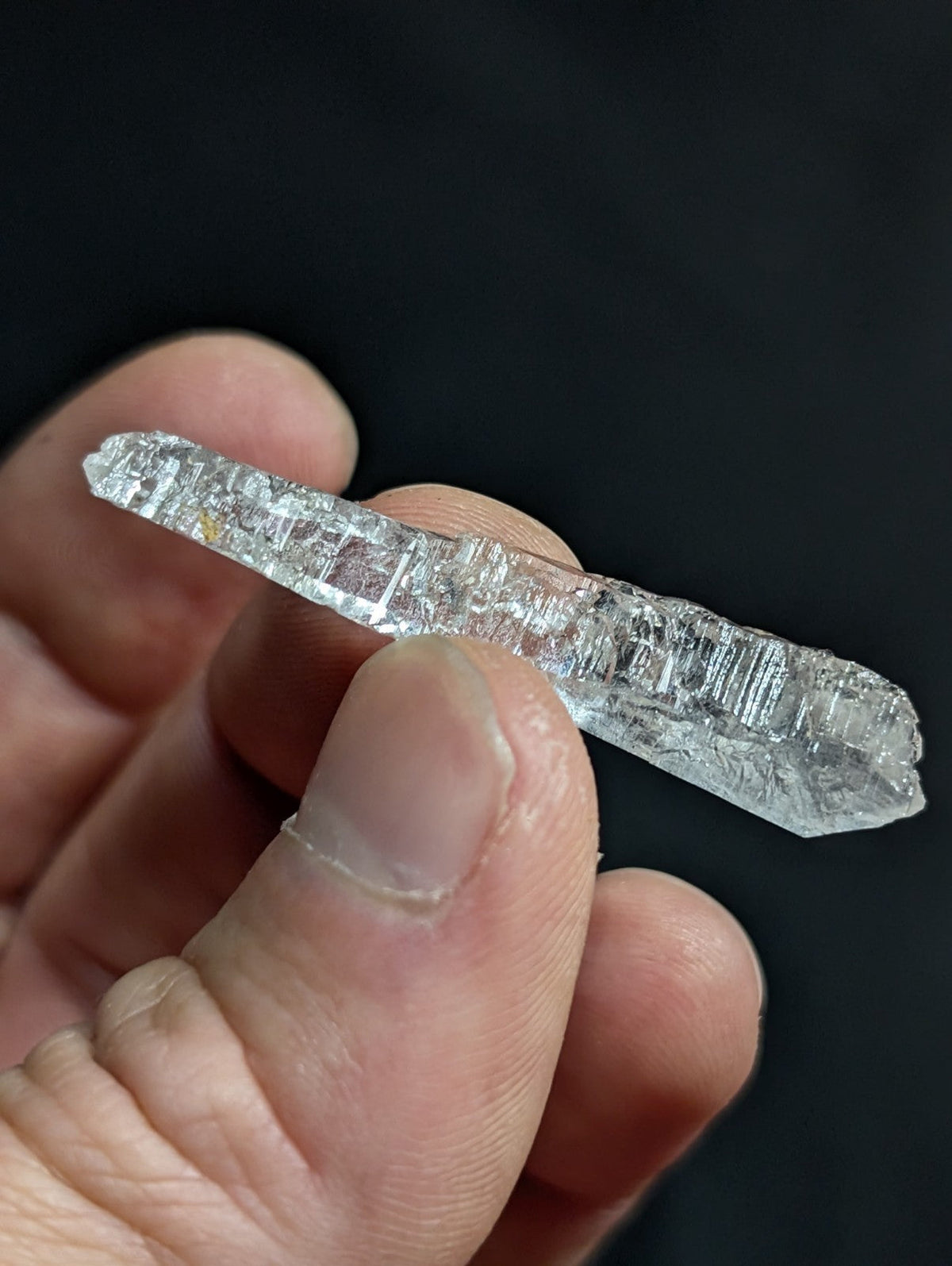 A clear, translucent quartz crystal with visible internal striations and a pointed tip.