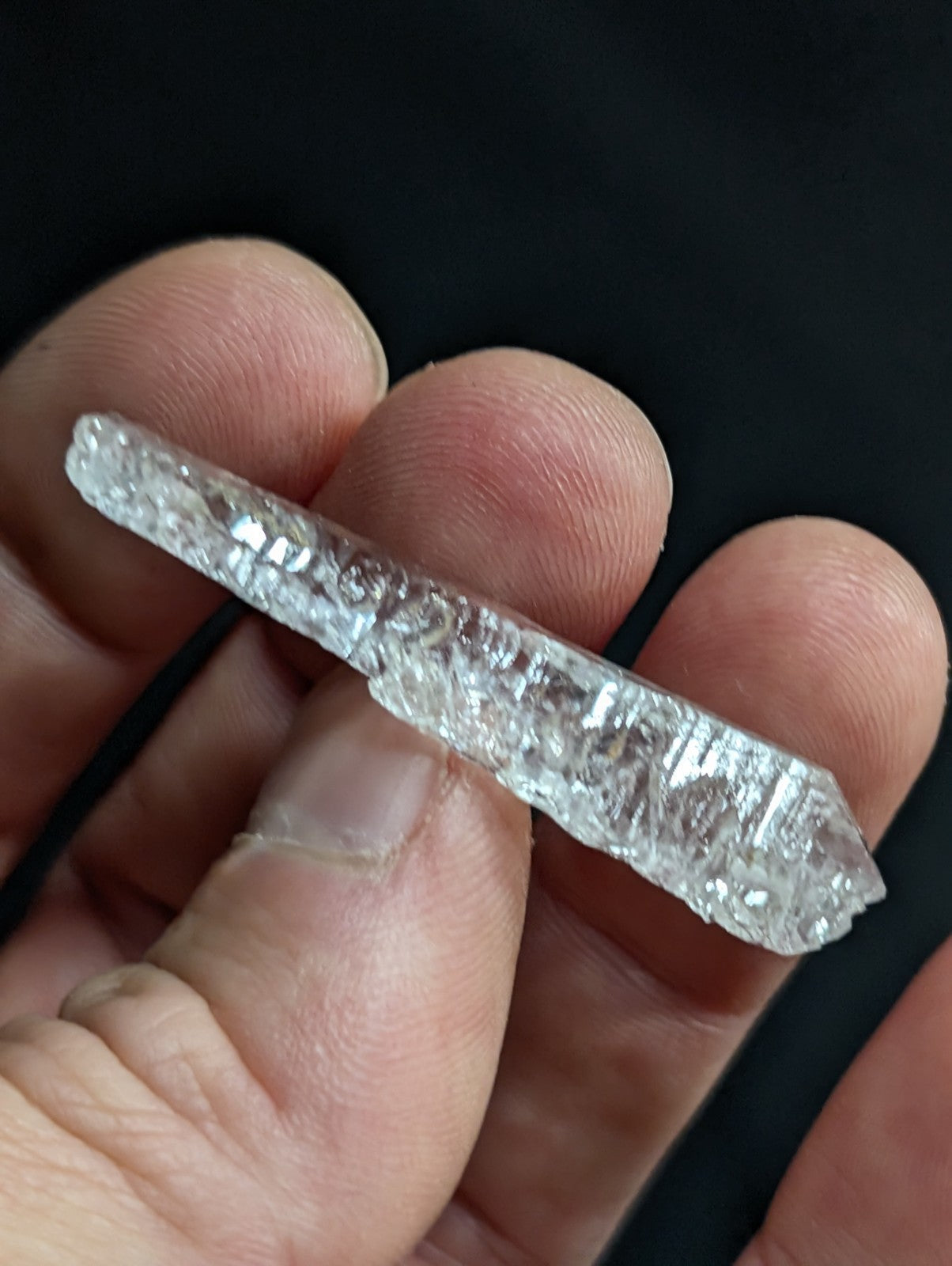 A clear, faceted raw diamond crystal with a natural, irregularly shaped surface and visible internal inclusions.