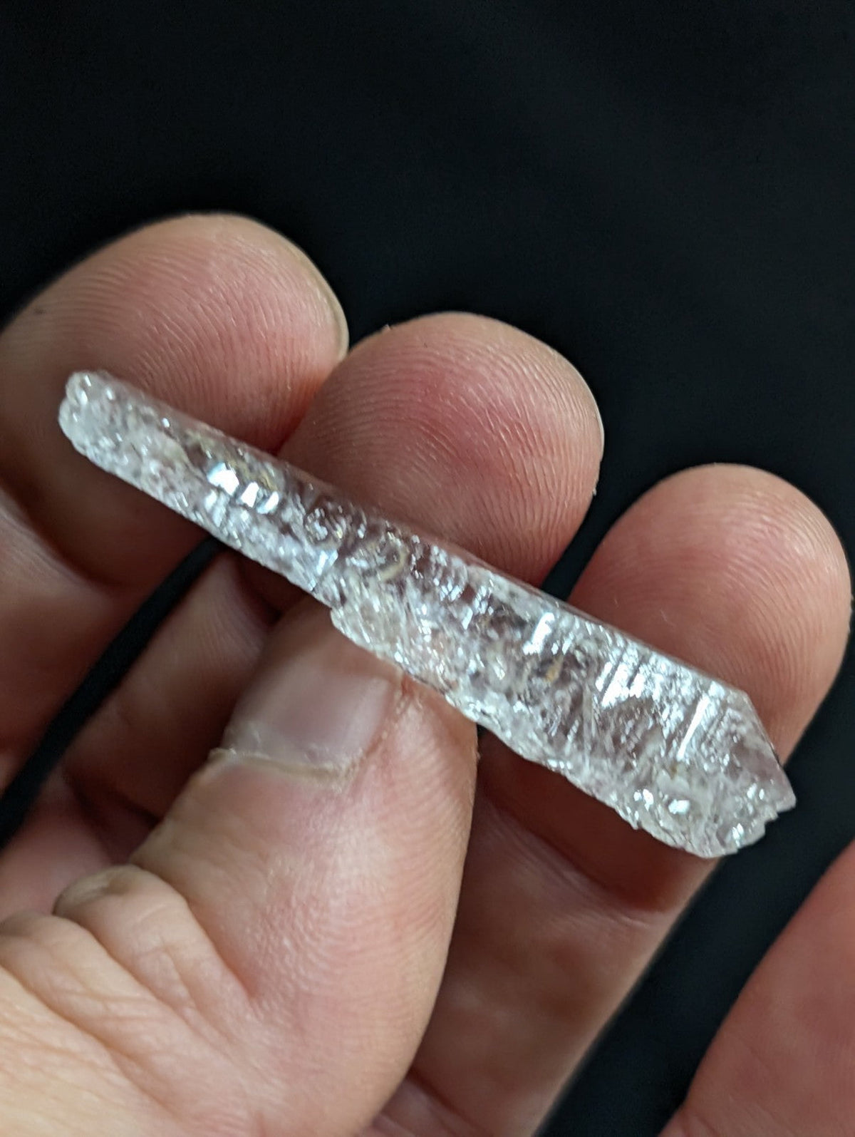 A clear, faceted raw diamond crystal with a natural, irregularly shaped surface and visible internal inclusions.