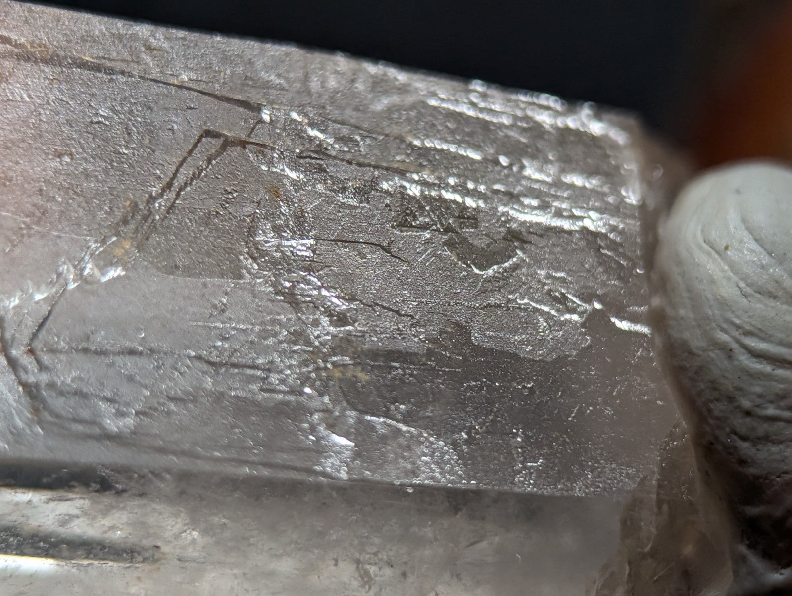 A rough, translucent quartz crystal with a metallic sheen and visible internal fractures.
