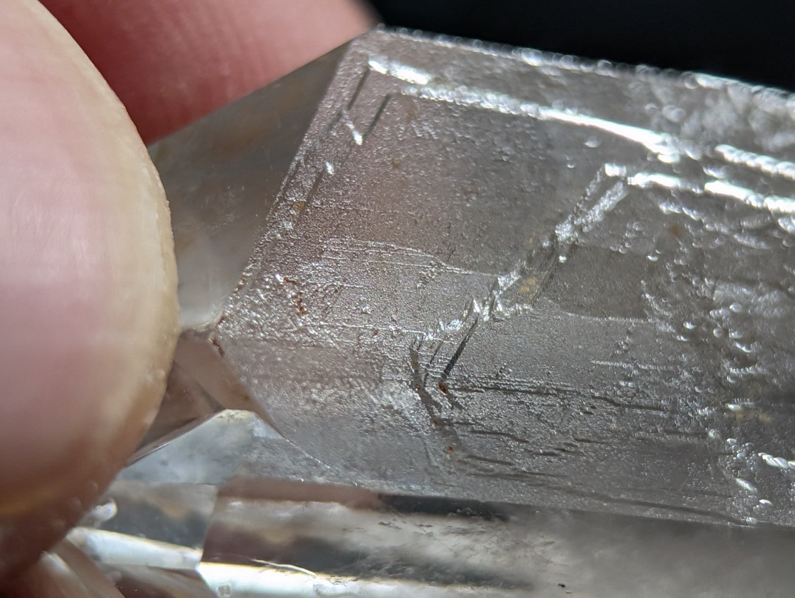 A translucent, silver-hued quartz crystal with visible internal striations and a faceted surface.