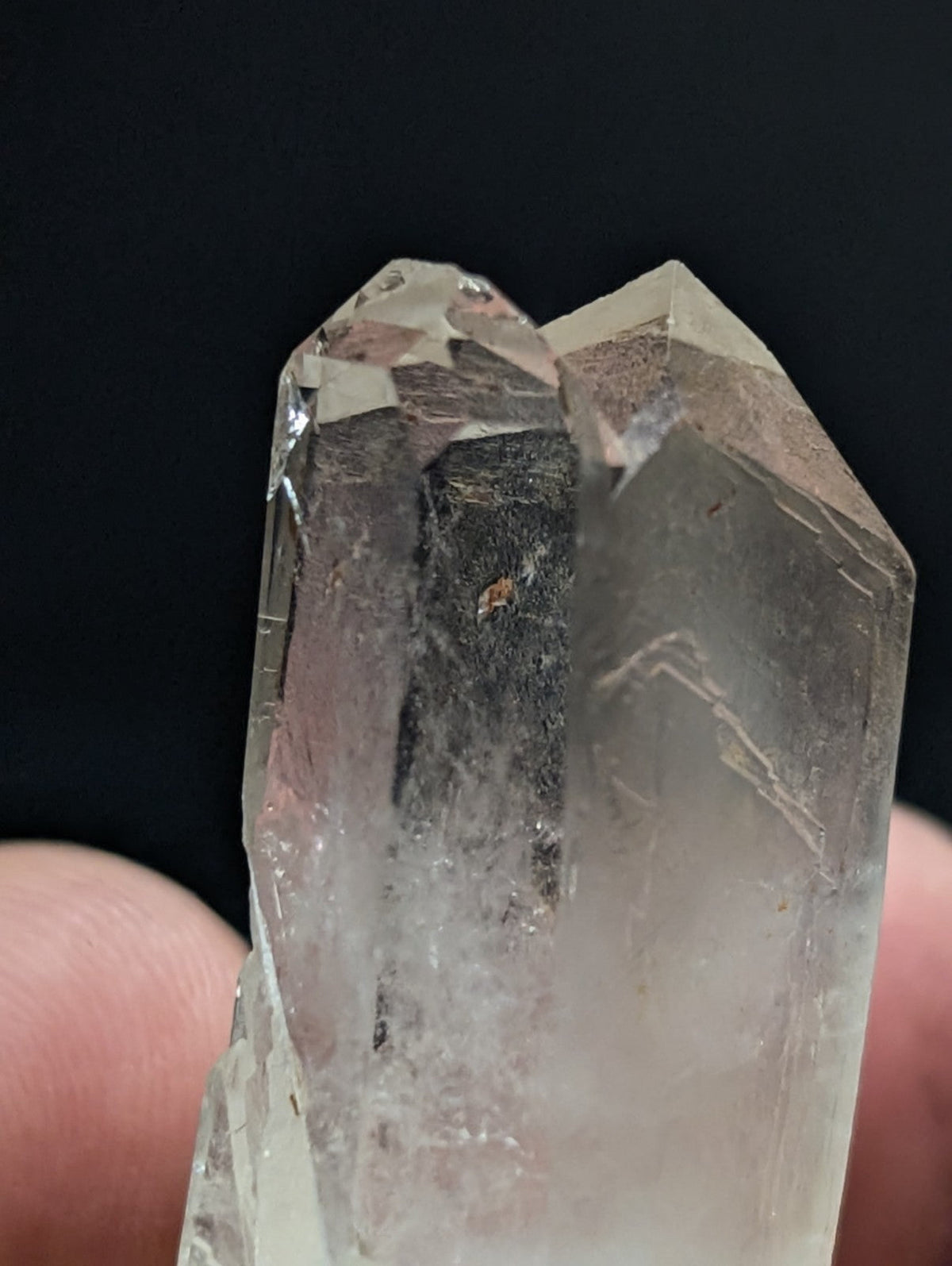 A translucent, clear quartz crystal with a pointed tip and visible internal inclusions.