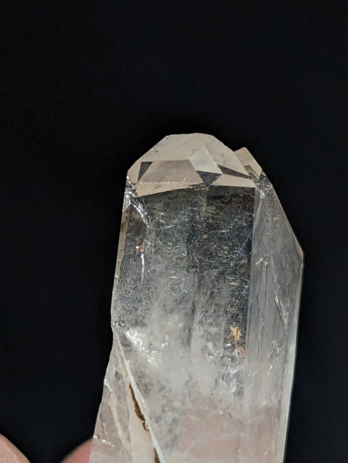 A clear, translucent quartz crystal with a pointed tip and visible internal inclusions.