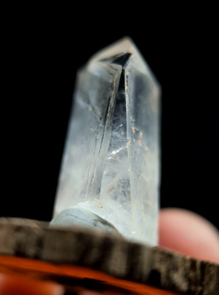 A clear, translucent quartz crystal with a pointed tip and visible internal striations.