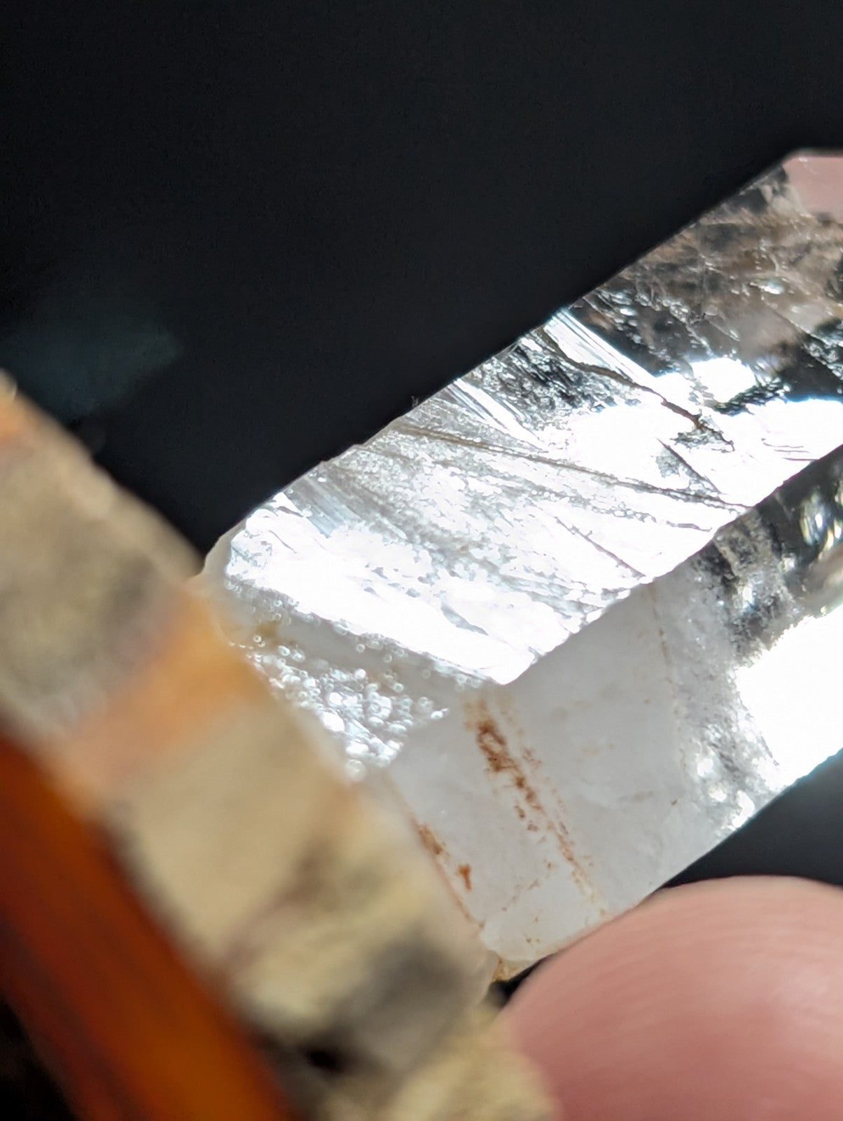A translucent, clear quartz crystal with visible internal striations and a few faint brown inclusions.
