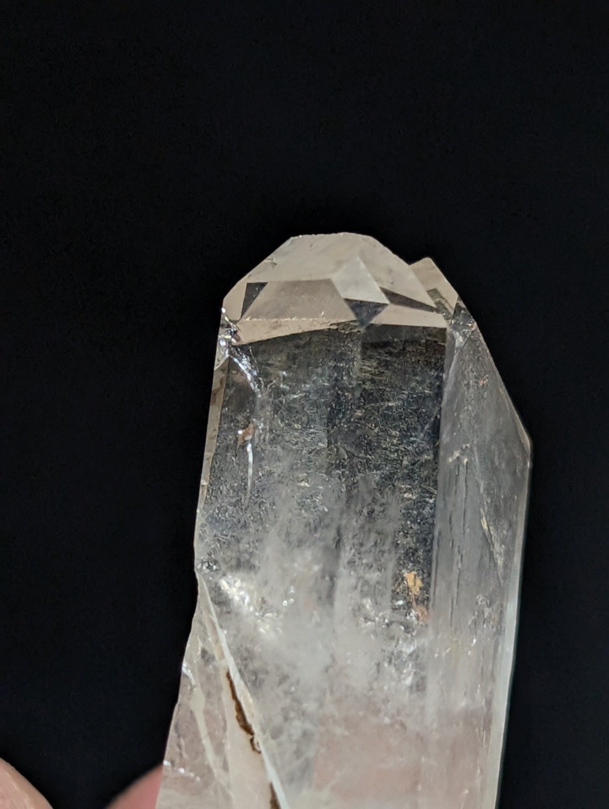 A clear, translucent quartz crystal with a pointed tip and visible internal inclusions.