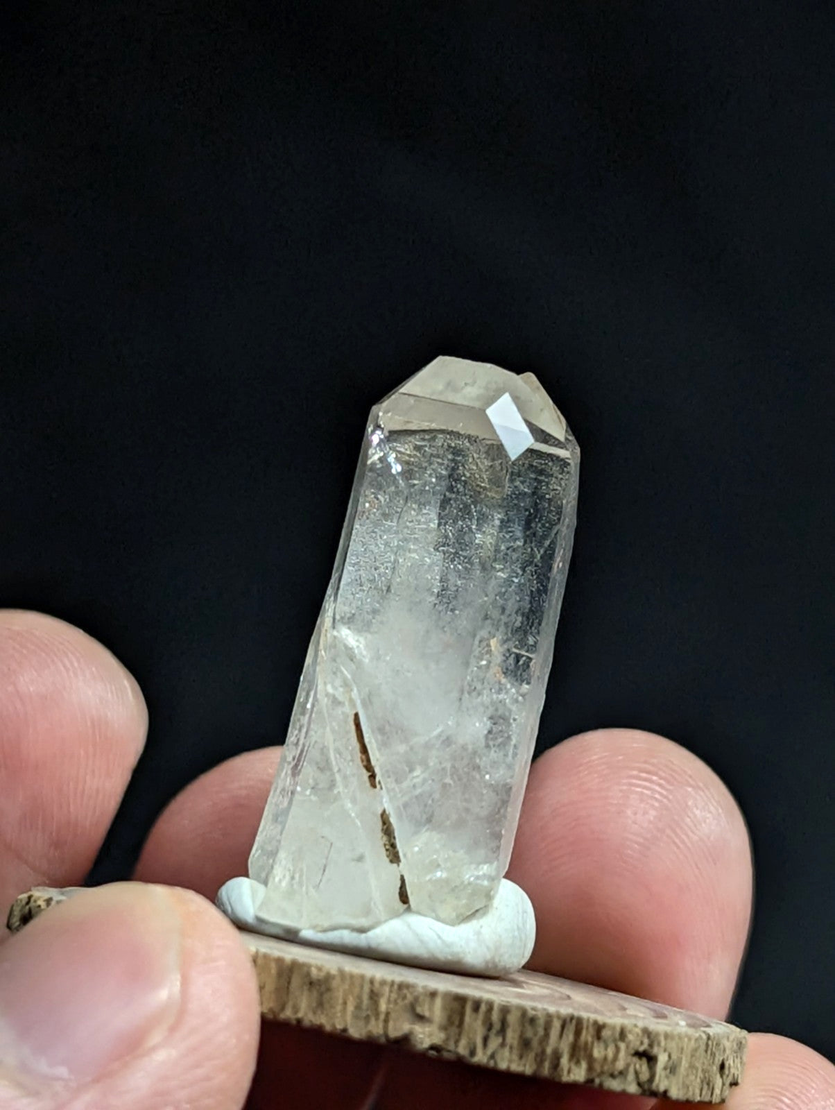 A clear, translucent quartz crystal with a pointed top and natural internal inclusions.