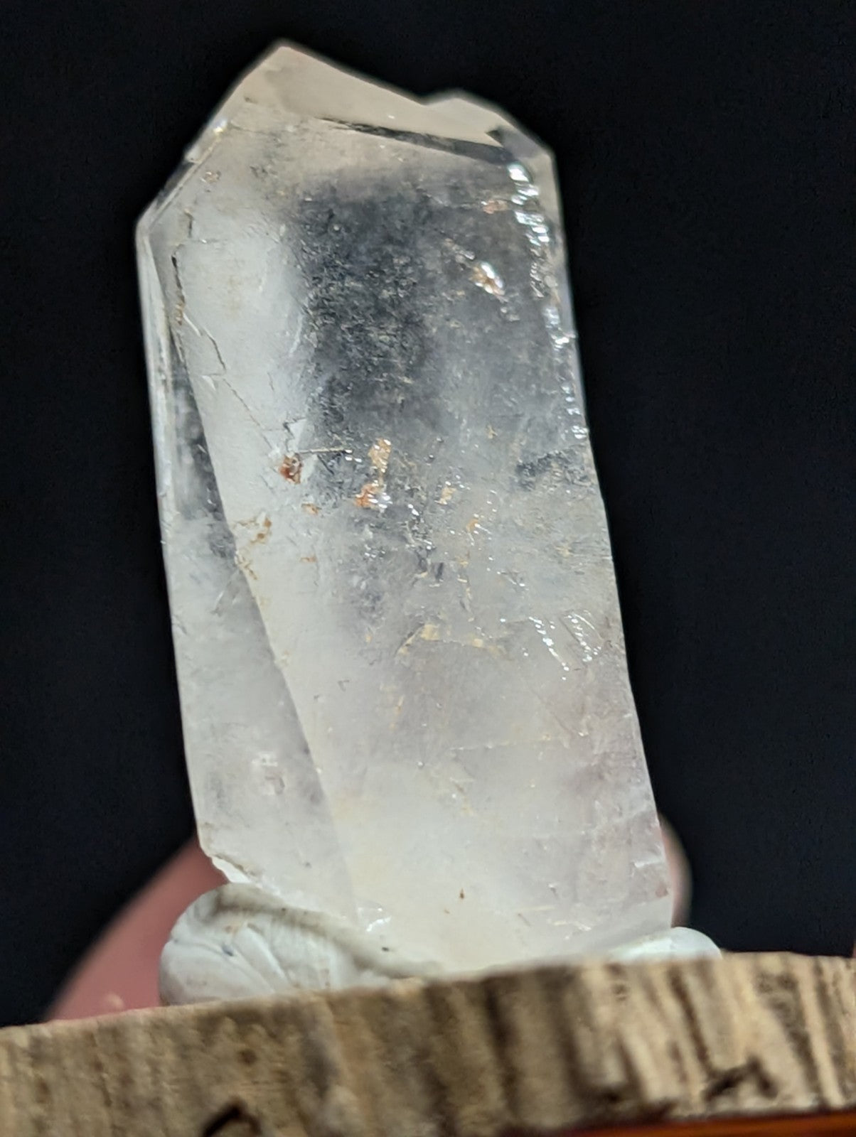 A translucent, clear quartz crystal with natural inclusions and a faceted top.