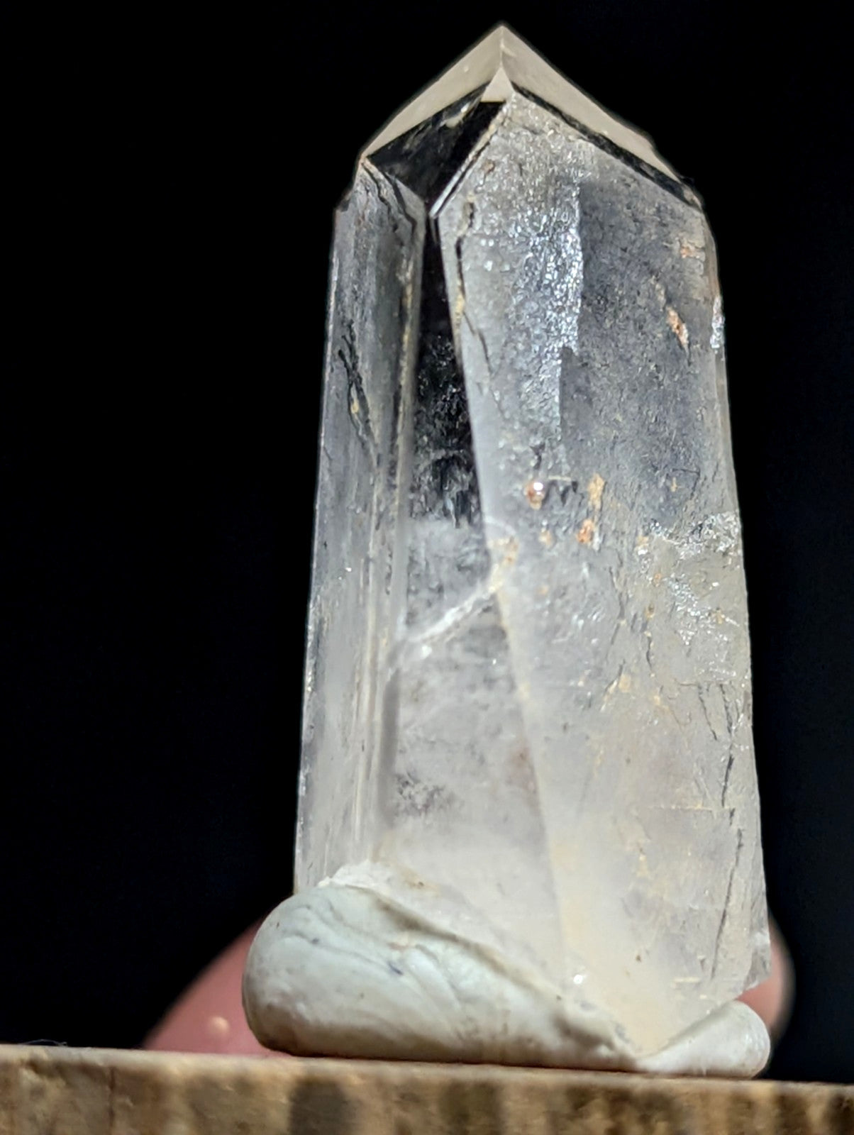 A translucent, clear quartz crystal with a pointed top and natural inclusions.