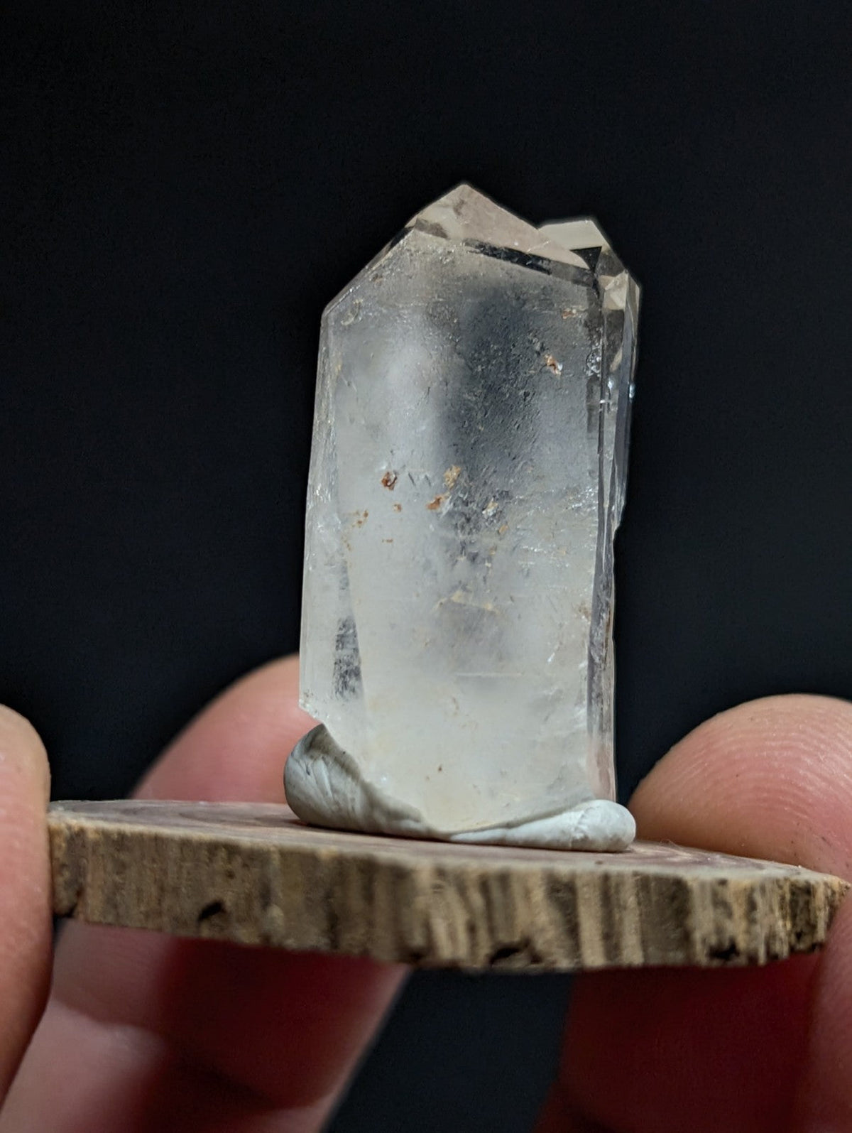 A translucent, clear quartz crystal with a rough, natural base and visible internal inclusions.