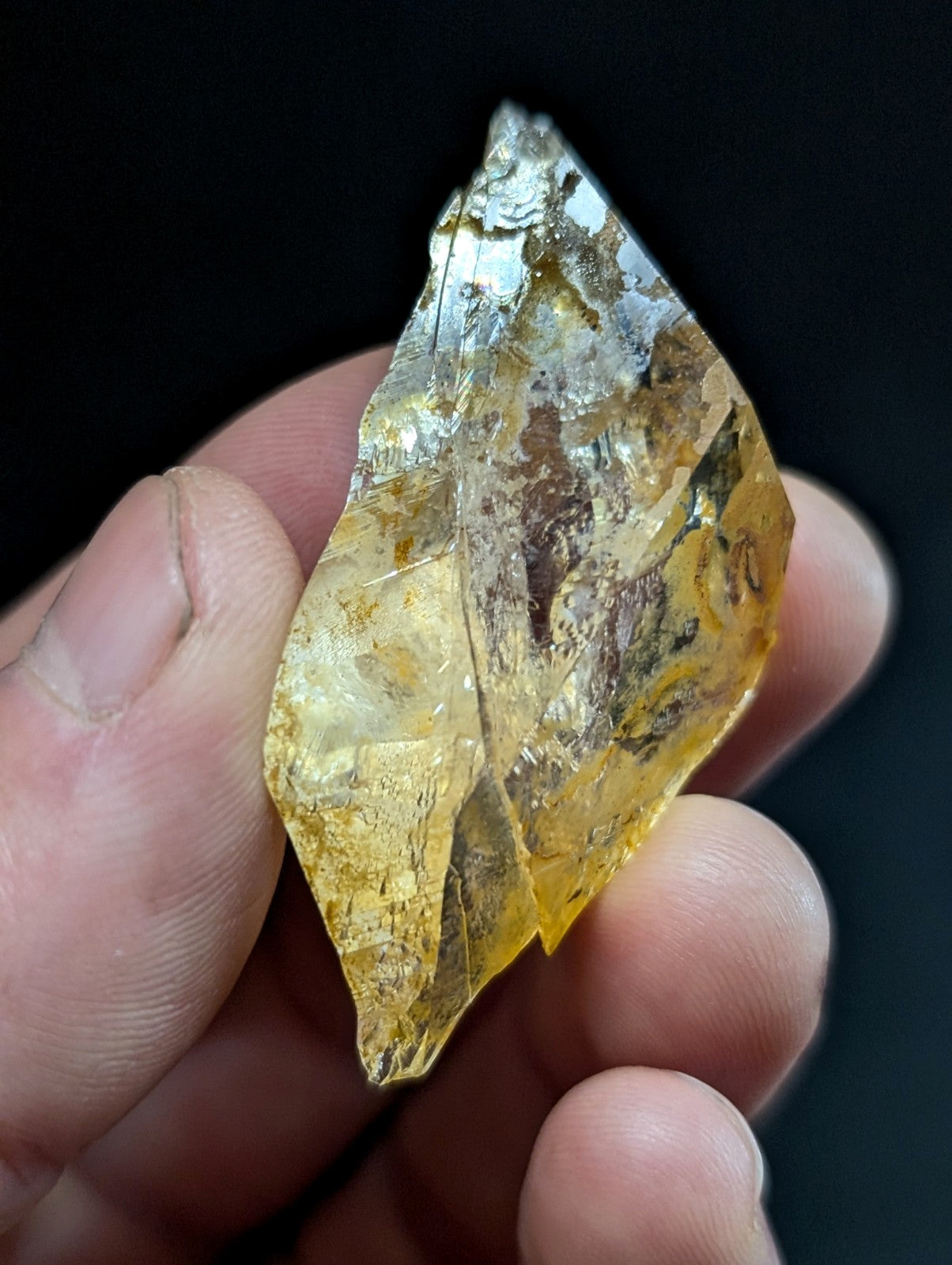 A translucent golden-yellow crystal with natural inclusions and a faceted, irregularly shaped surface.