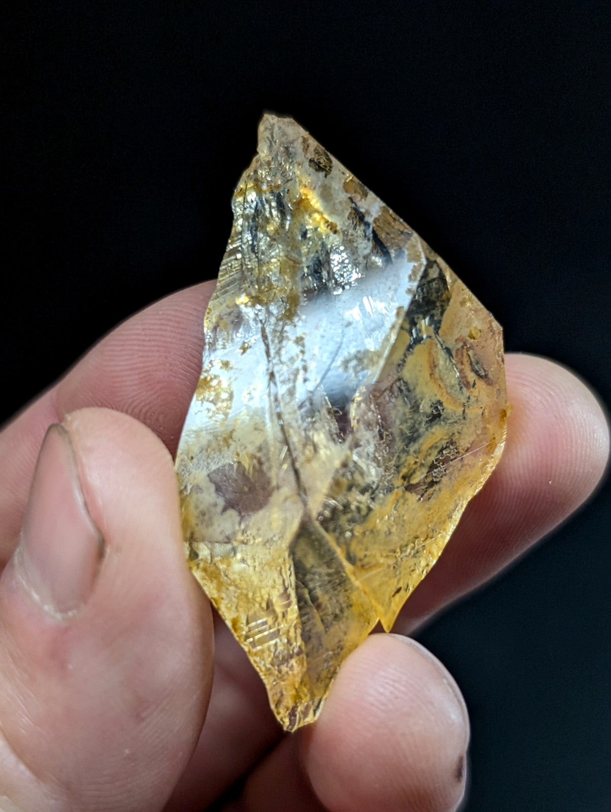 A translucent golden-yellow crystal with embedded metallic inclusions and a faceted, irregular shape.