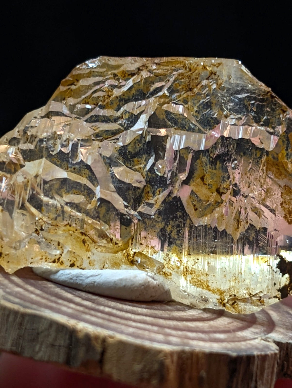 Unique etched quartz crystal point in golden yellow with layered facets and mineral inclusions on wooden base from arkansas