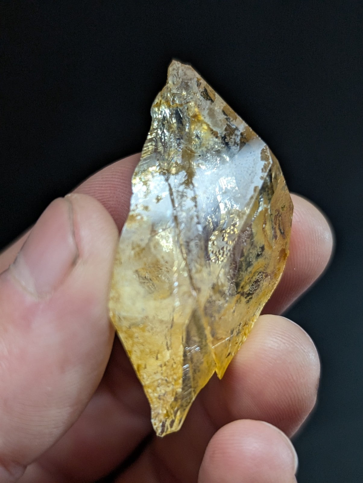 A translucent amber-colored, irregularly shaped mineral specimen with golden inclusions and a glossy surface.