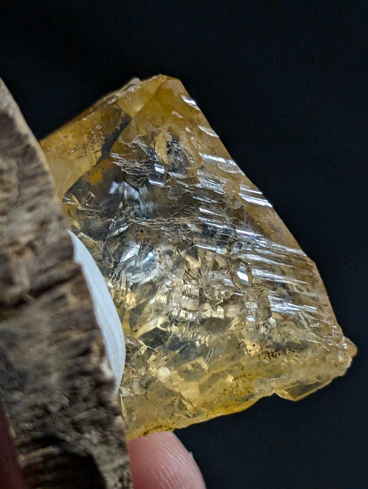 A translucent golden-yellow crystal with visible internal striations and a rough, faceted surface.