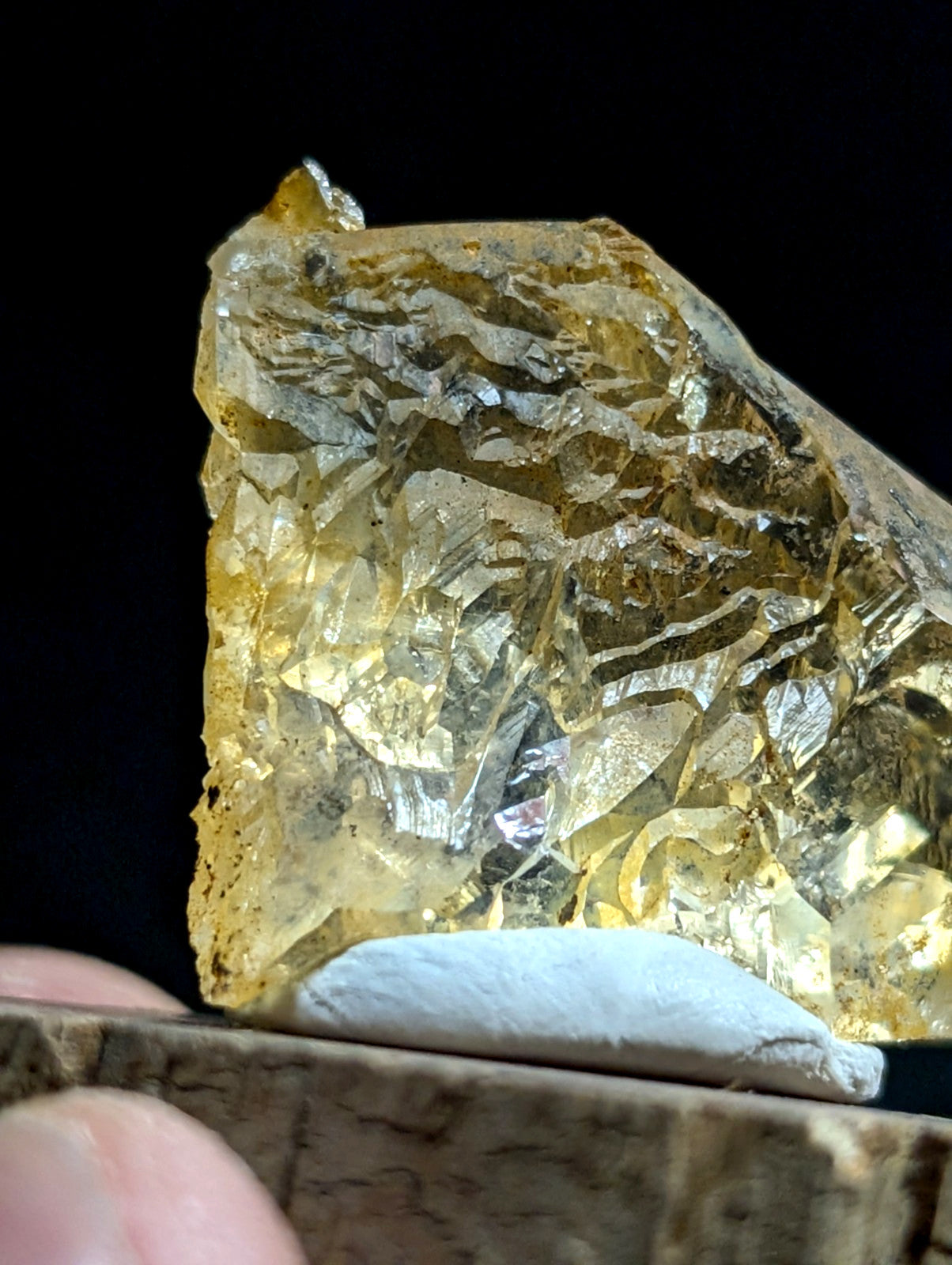 A translucent golden-yellow crystal with a rough, faceted surface and visible internal striations.