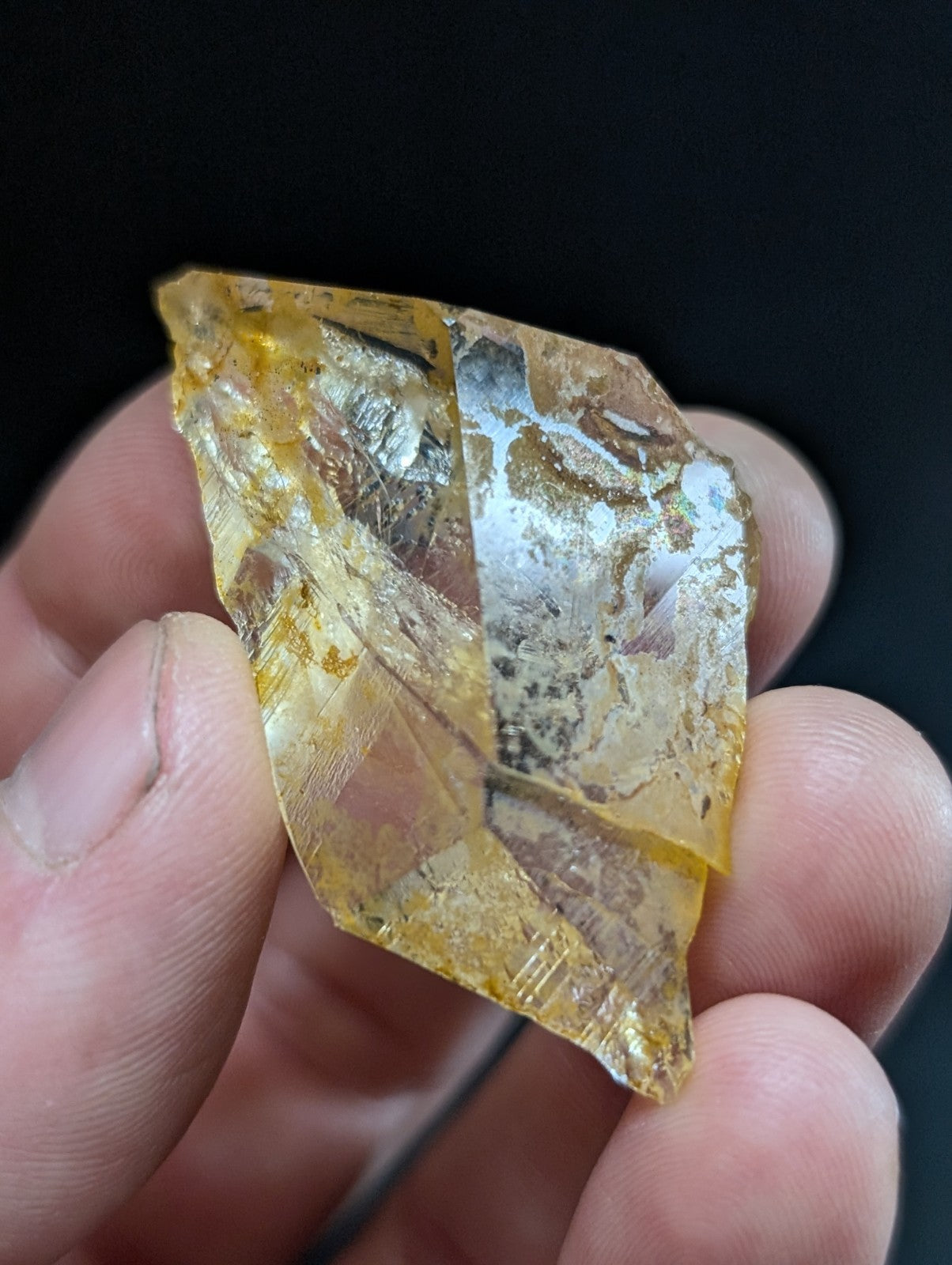 A translucent yellow crystal with a metallic silver inclusions and sharp, angular facets.