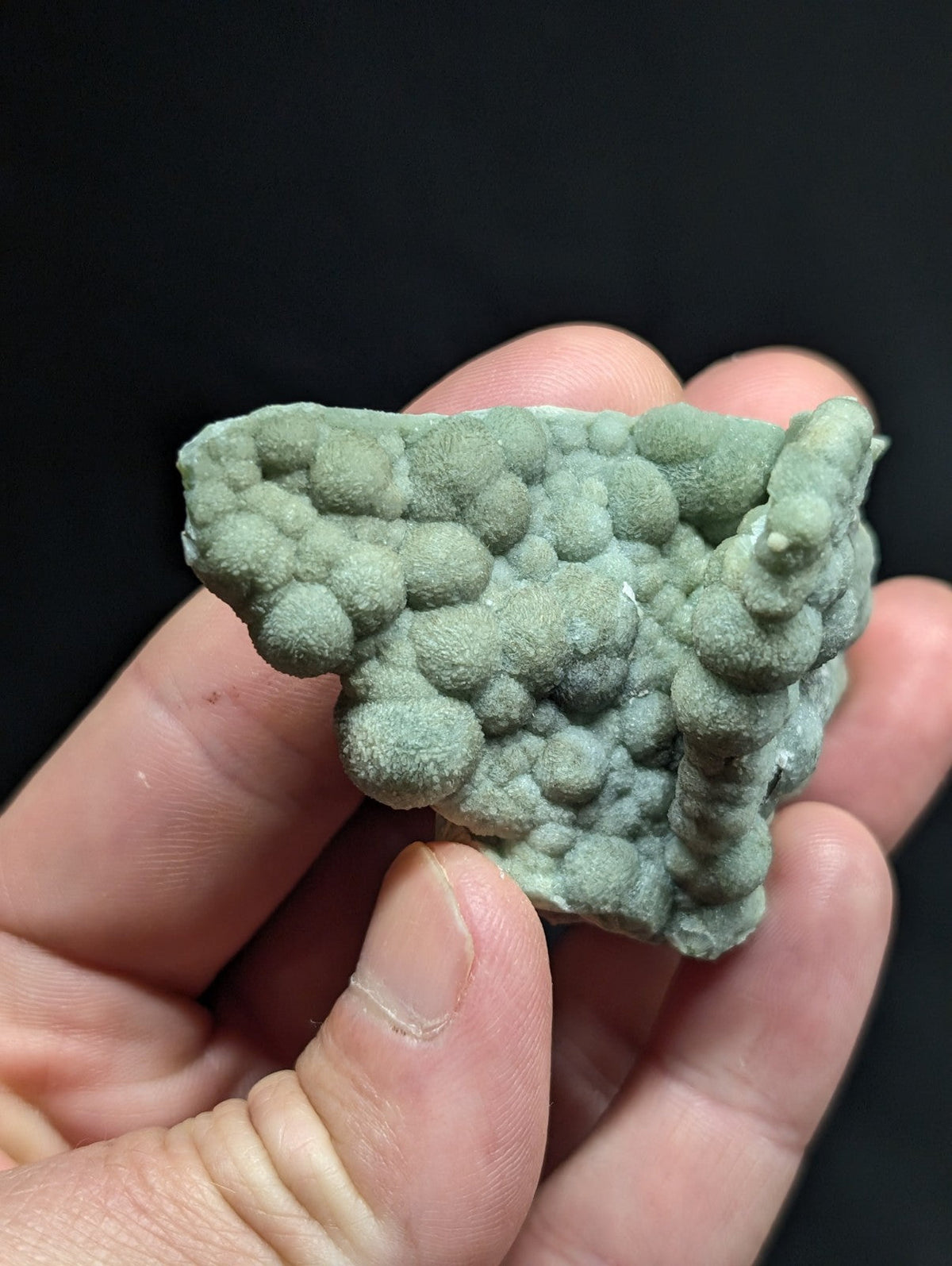 A textured, light green mineral specimen with a bumpy, bubble-like surface.