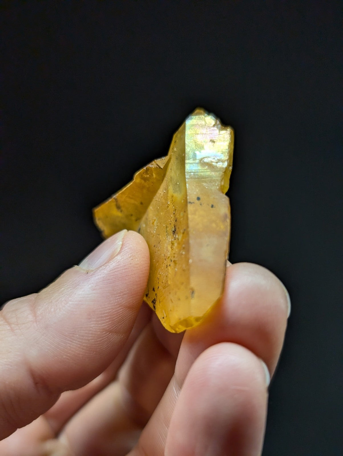 A translucent golden-yellow crystal with a faceted, pointed tip and subtle iridescent sheen.