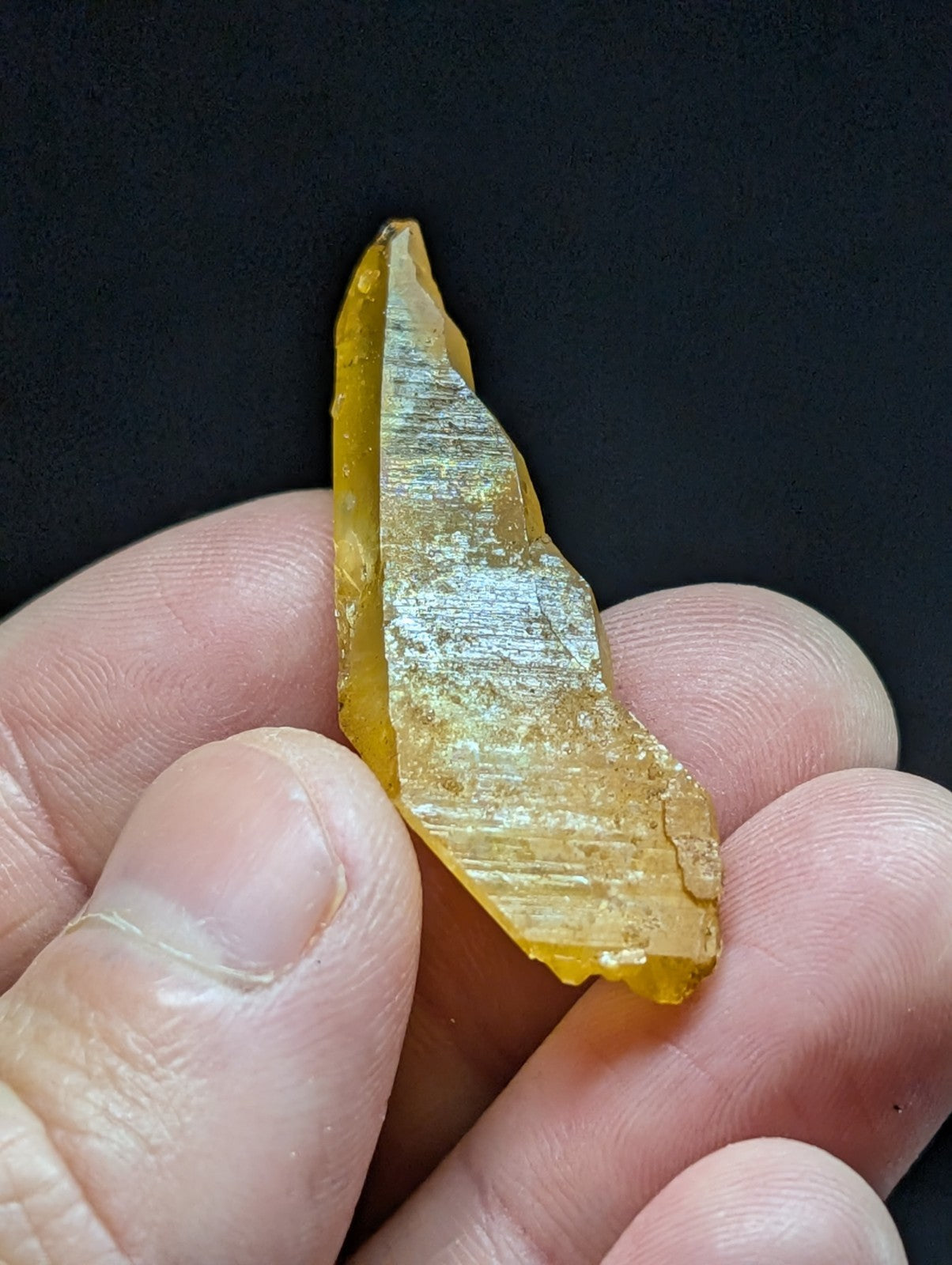 A translucent amber-colored, irregularly shaped piece of natural resin with visible internal striations and a slightly rough texture.