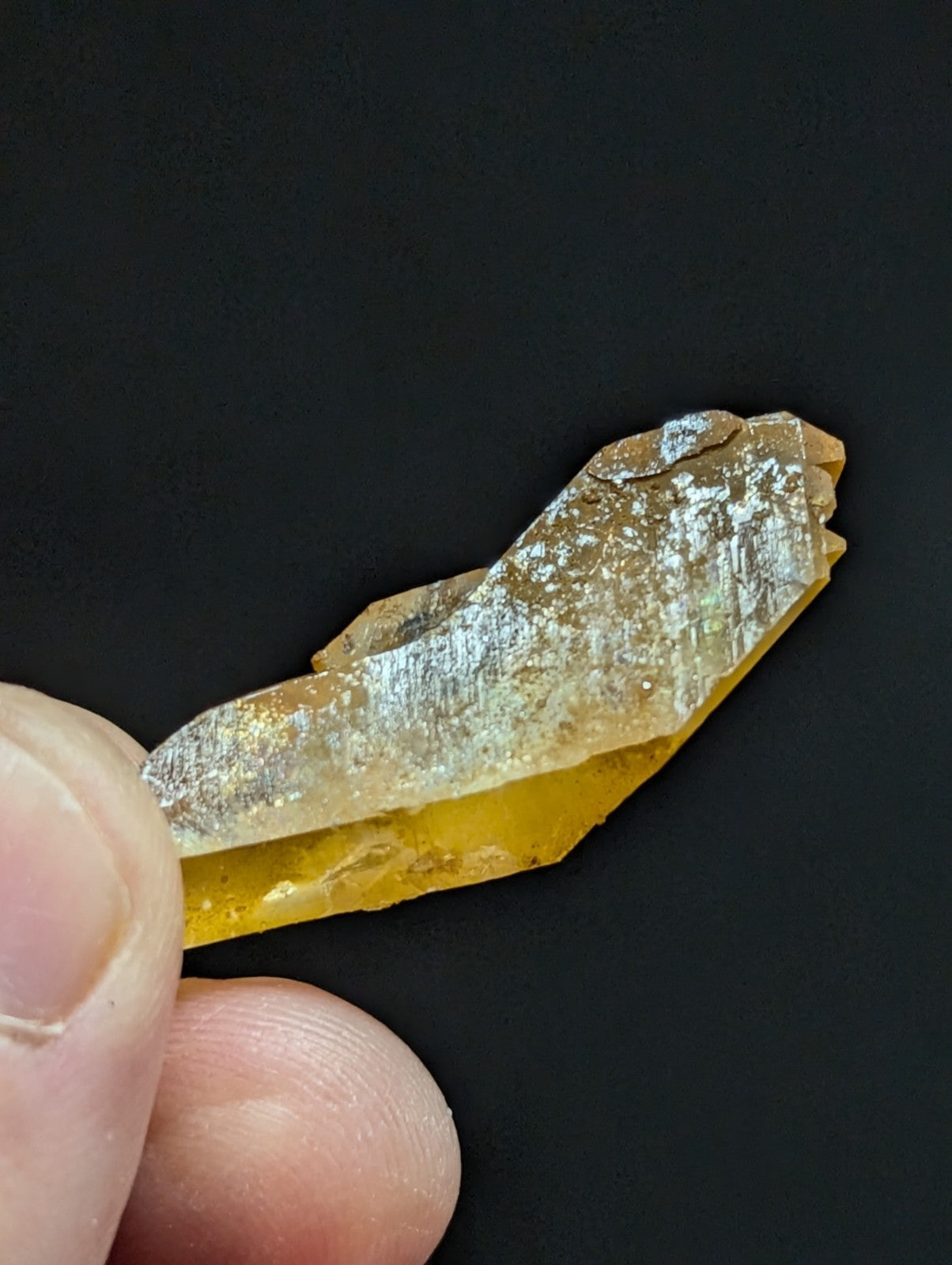 A translucent golden-yellow crystal with a metallic sheen and natural, jagged edges.