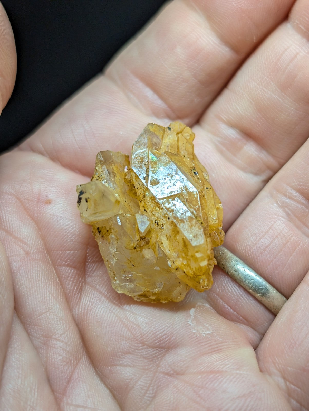 A cluster of translucent yellow crystals with sharp, faceted edges and some dark mineral inclusions.