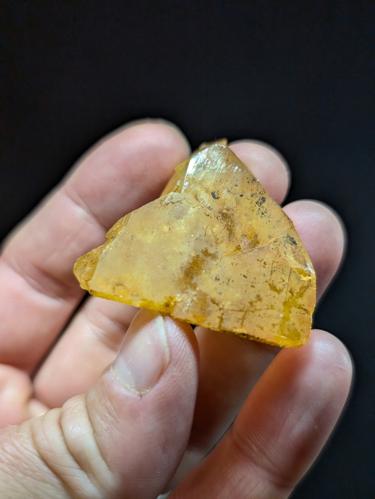 A translucent amber-colored crystal fragment with a rough, irregular surface and visible internal inclusions.