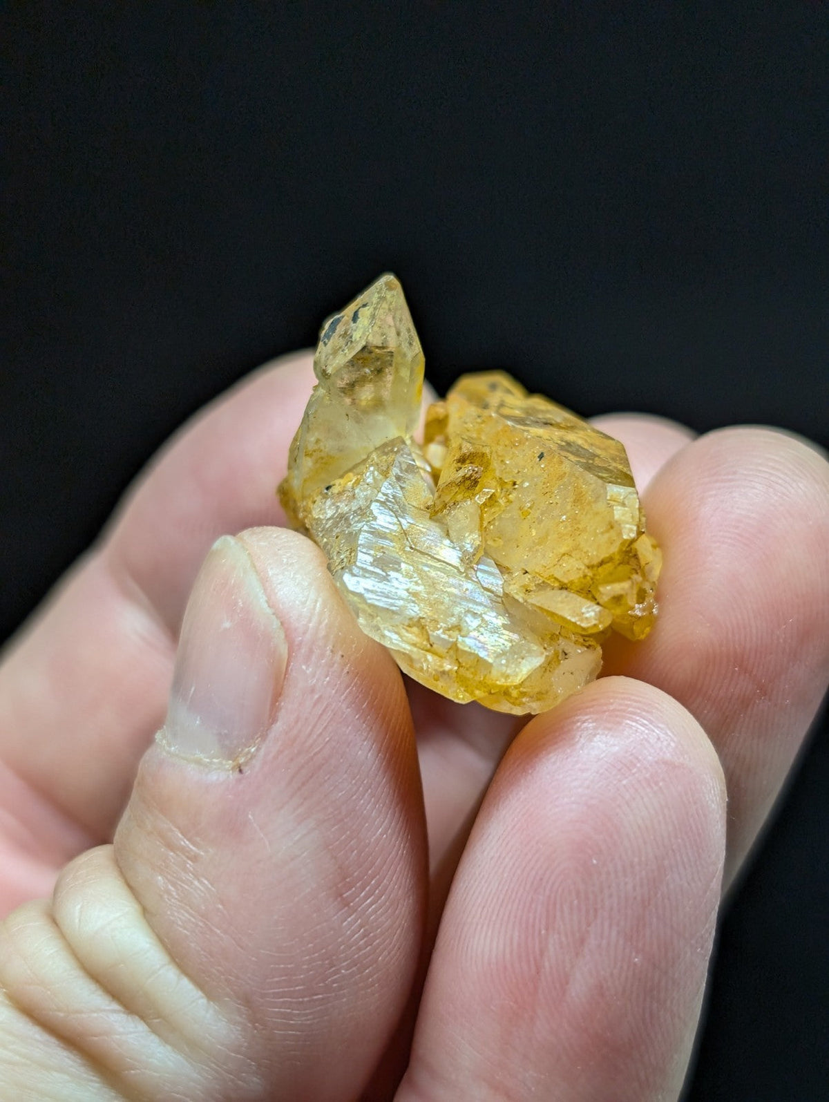 A cluster of translucent yellow crystals with sharp, faceted edges held gently in a hand.