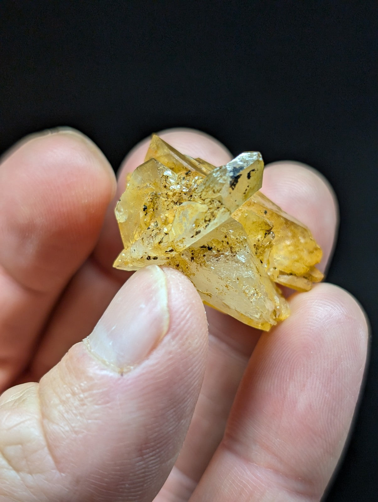 A translucent yellow crystal cluster with sharp, angular facets and embedded dark inclusions.