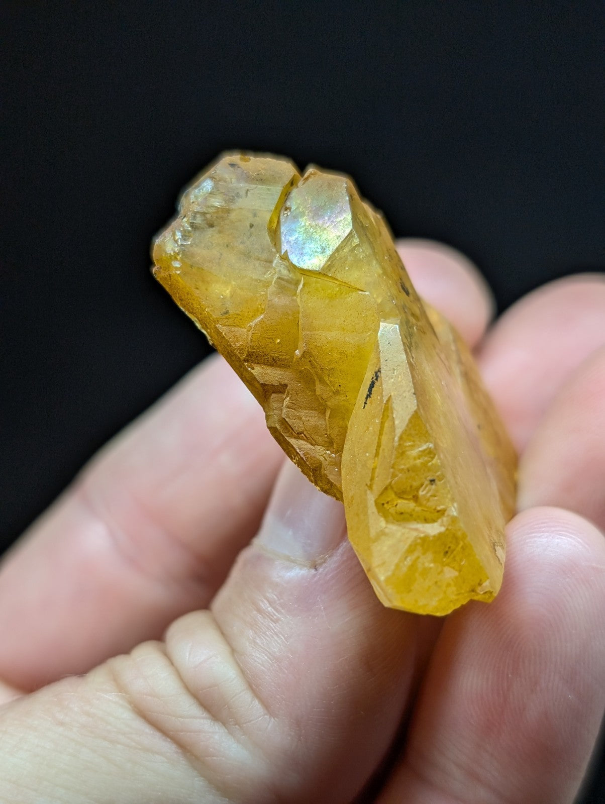 A translucent golden-yellow crystal with a faceted, natural mineral structure and subtle iridescent highlights.